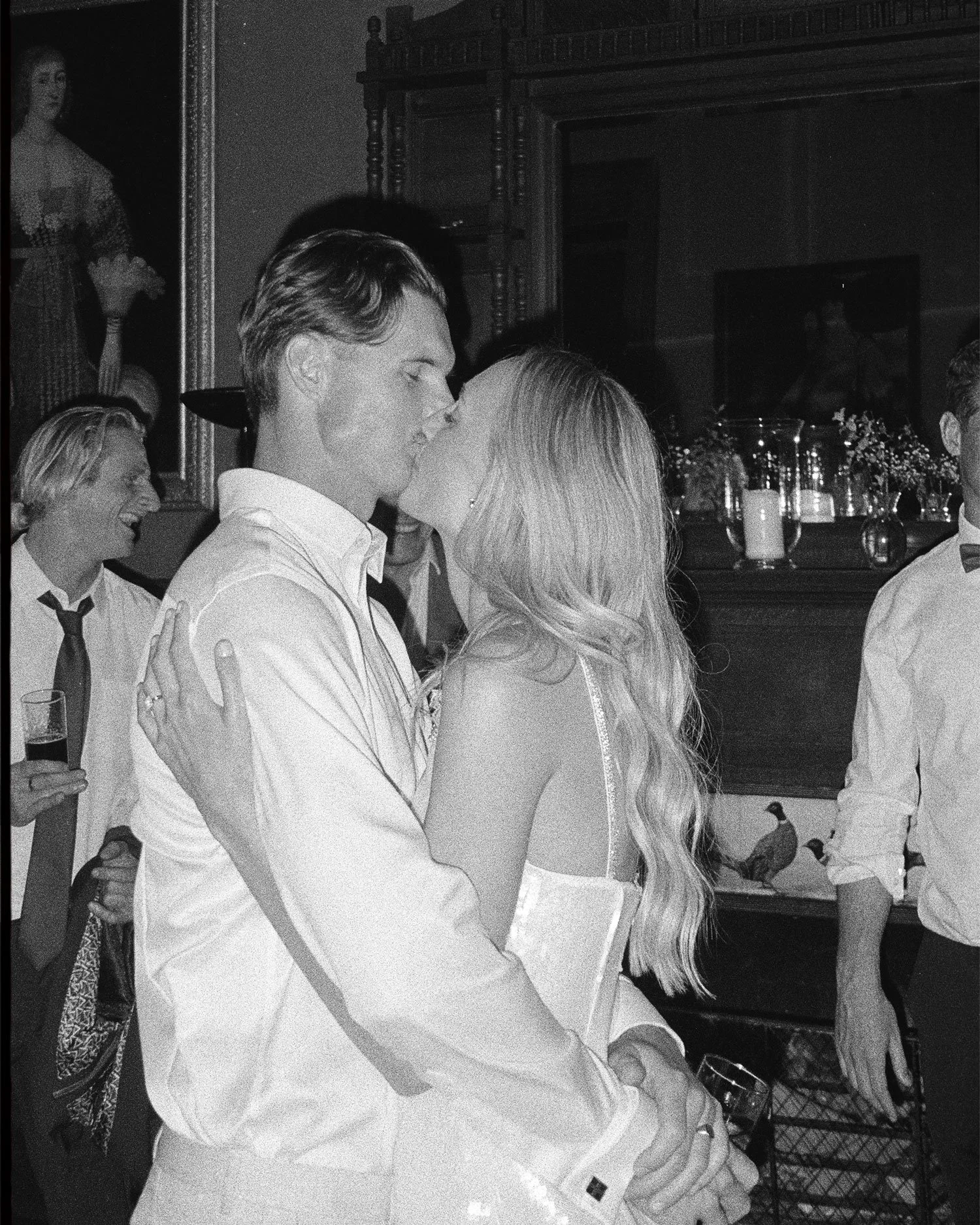 Black and white 35mm film wedding photograph of couple kissing during reception, documentary storytelling approach