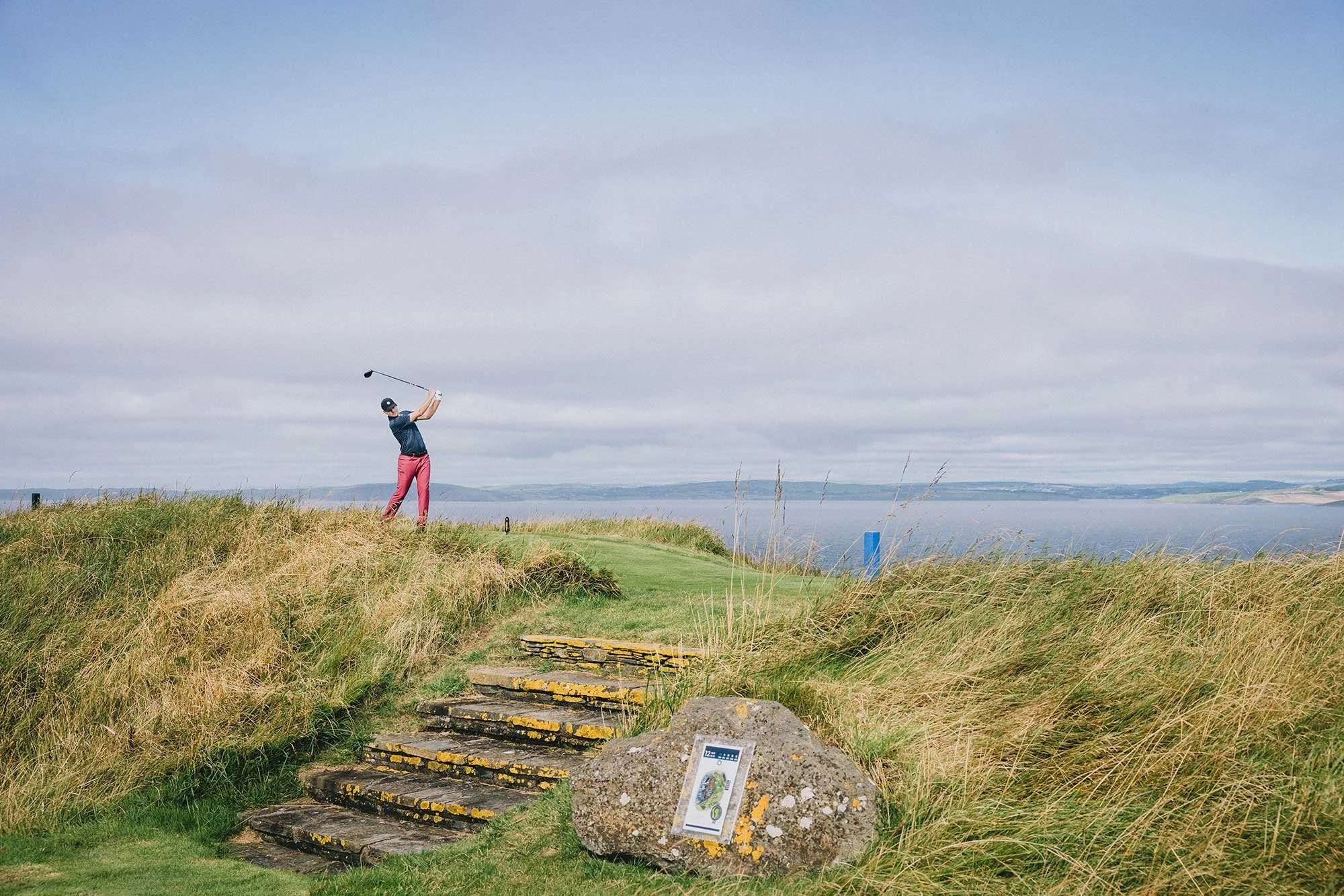Golfer playing from an elevated coastal tee above the sea