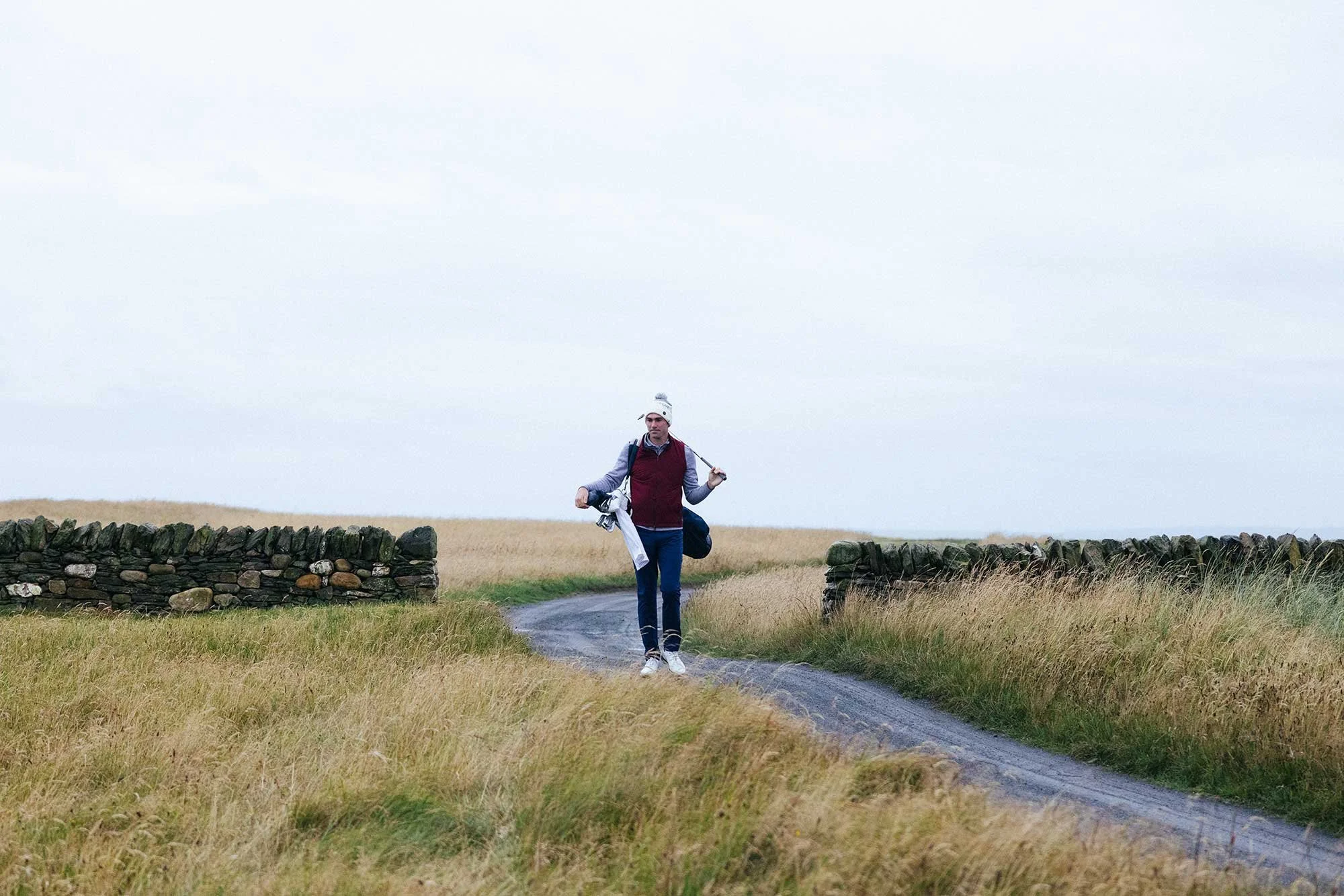 Golfer walking through the links landscape at The Machrie in Scotland, photographed for Holderness & Bourne.