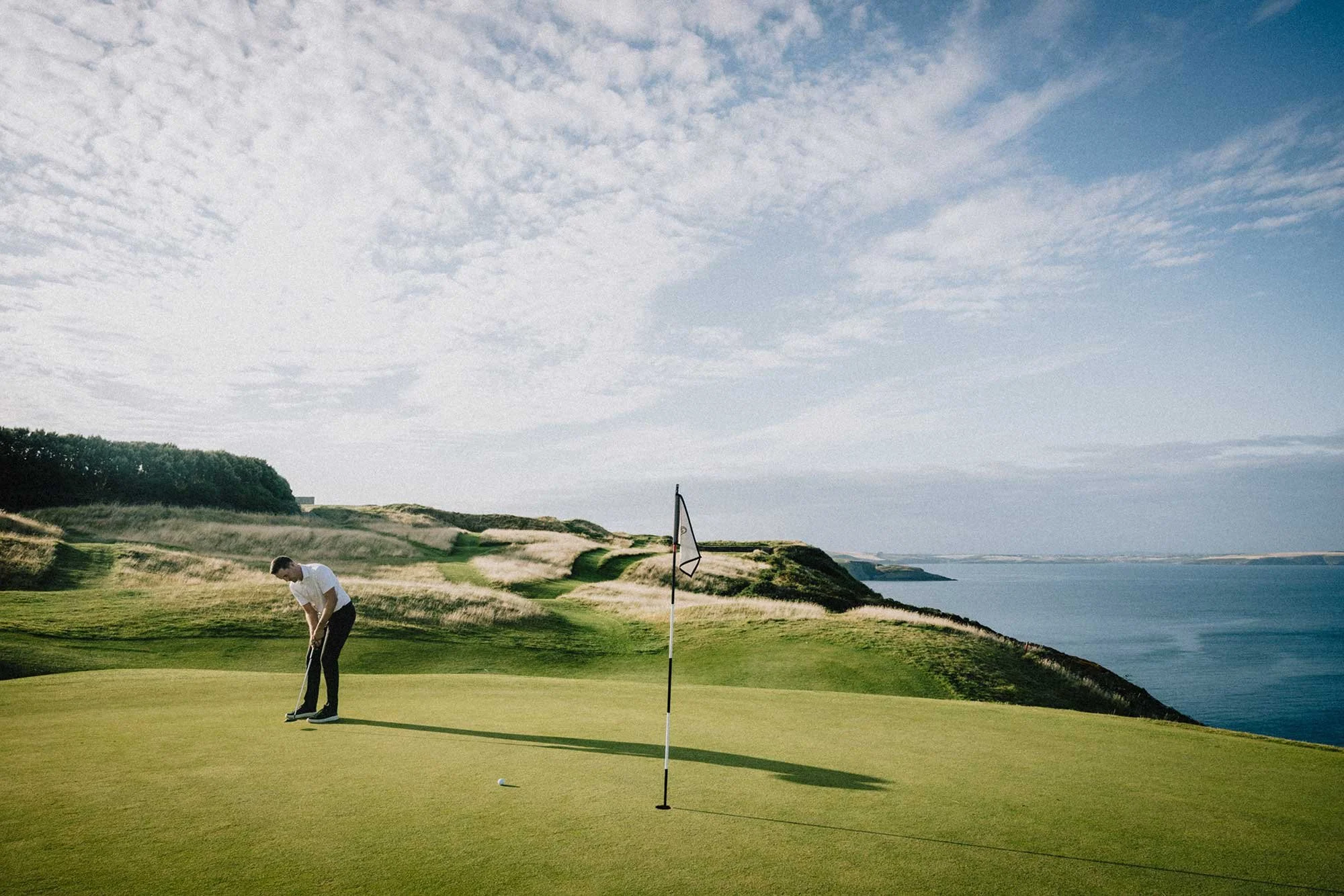 Golfer putting on a coastal green at Old Head Golf Links in Ireland