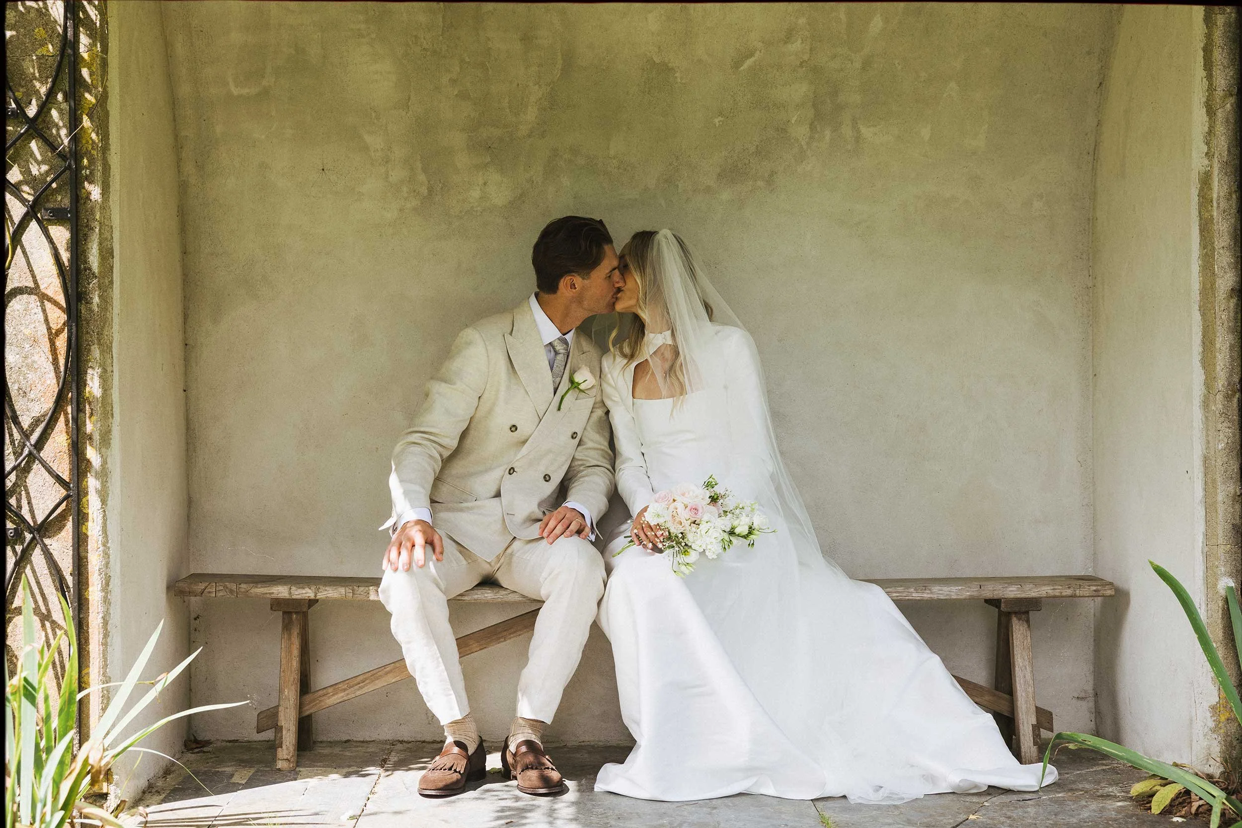 35mm film wedding portrait of couple seated in garden pavilion, intimate documentary style