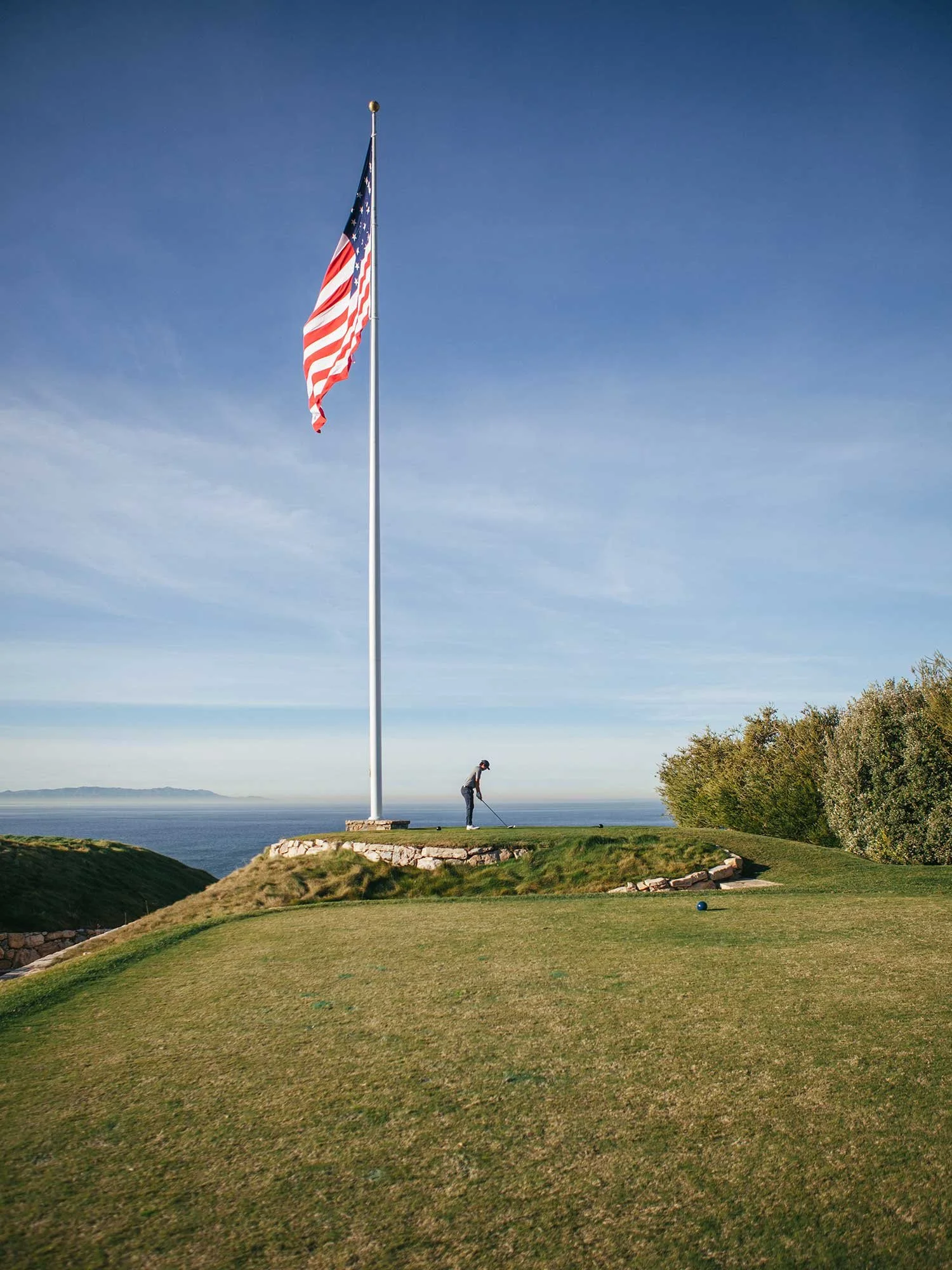 Golfer playing beneath a large American flag on a coastal course