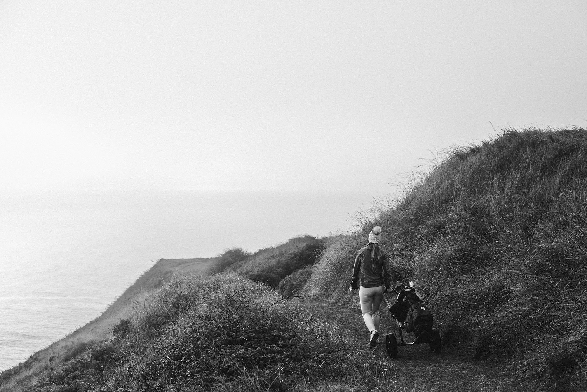 Golfer Hannah Gregg walking the coastal course at Old Head Golf Links in Ireland, photographed by Karl Mackie.