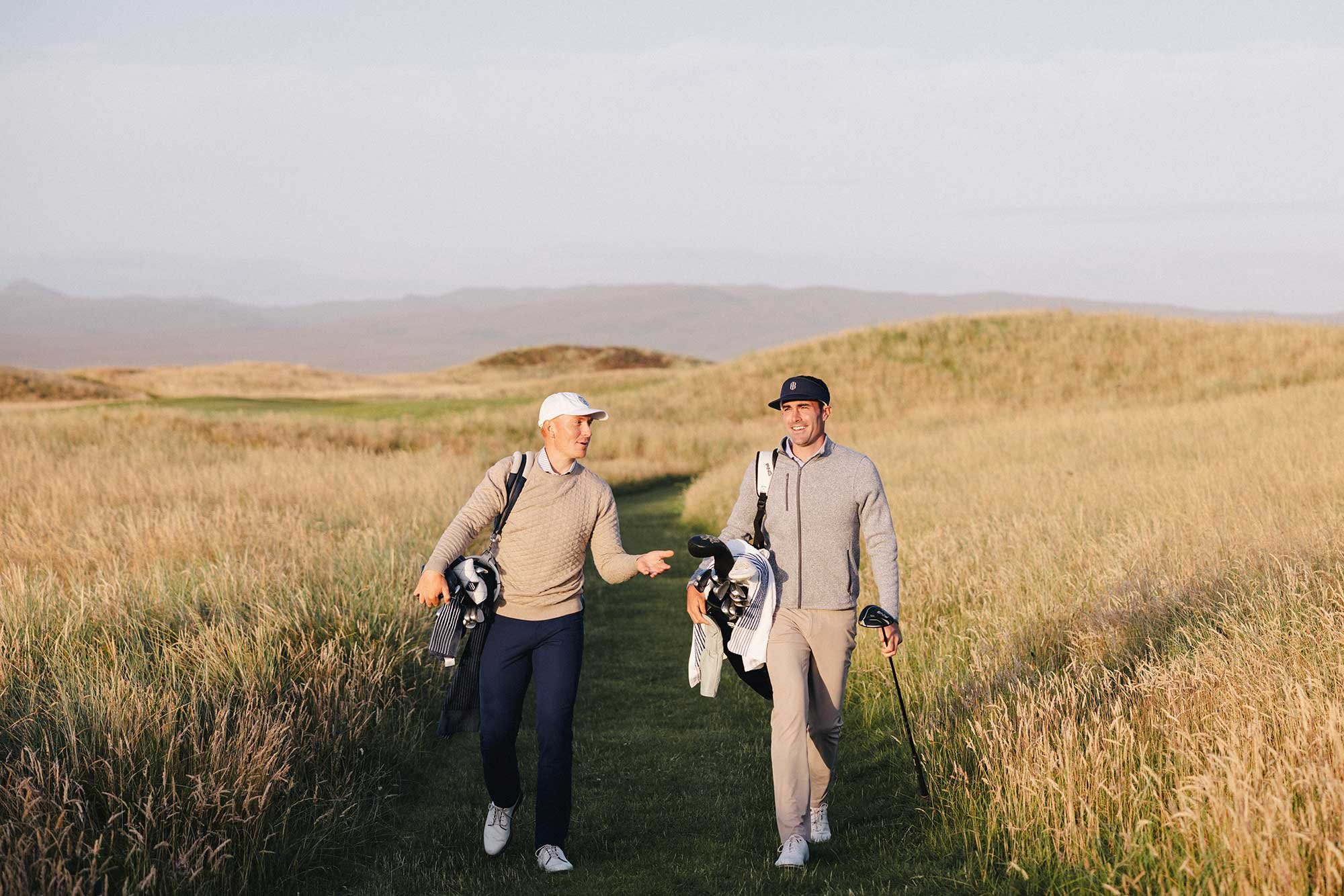 Two golfers walking together through golden links rough