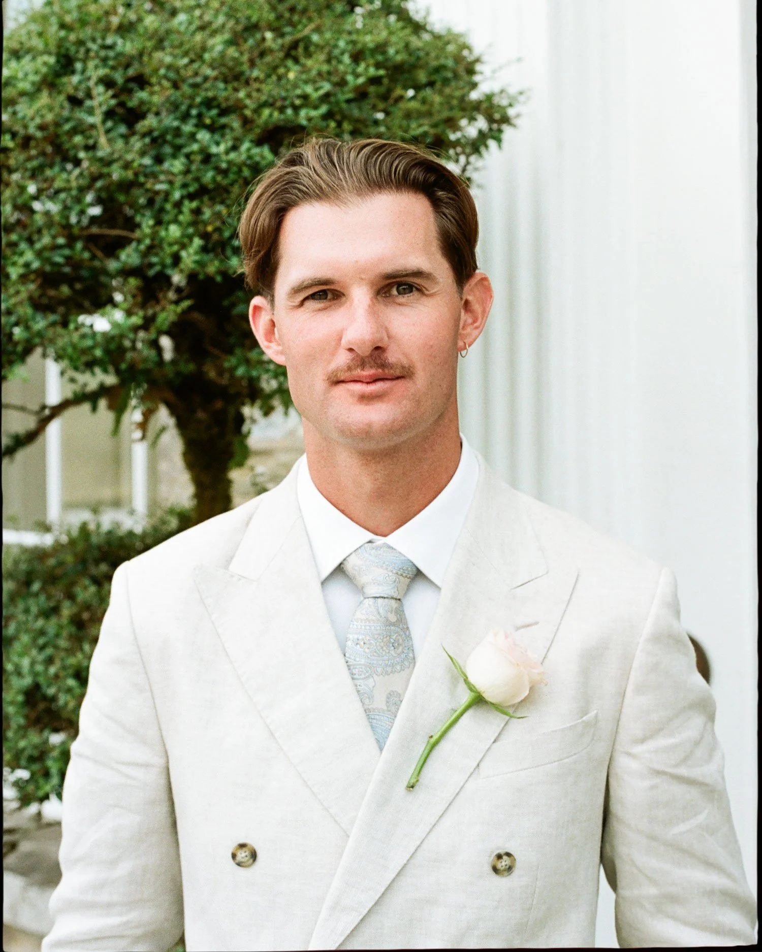 Editorial film wedding portrait of groom in cream suit at Boconnoc House and Estate, natural light documentary photography