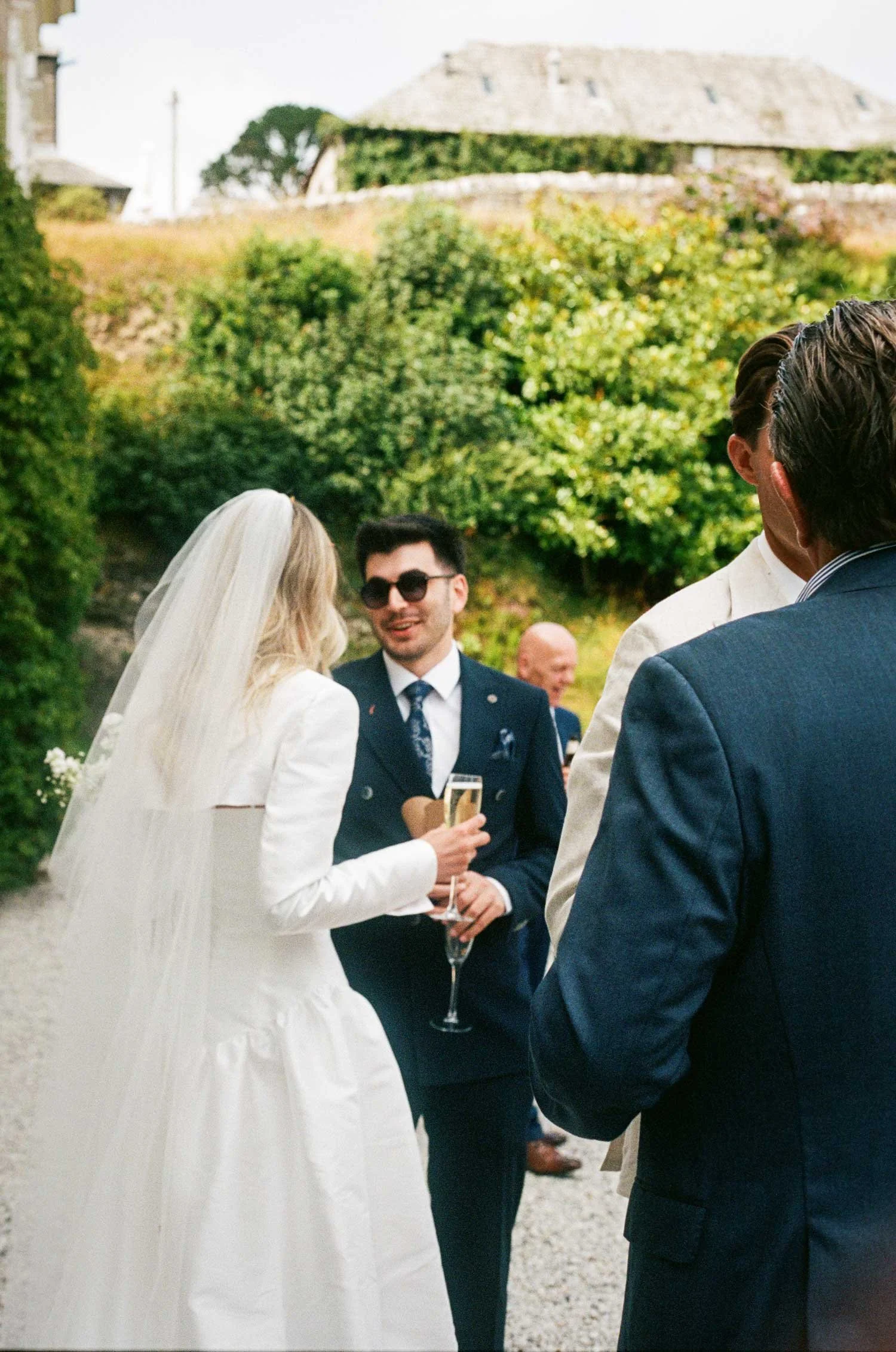 Documentary wedding photography on 35mm film, bride talking with guest outside country house venue in Cornwall
