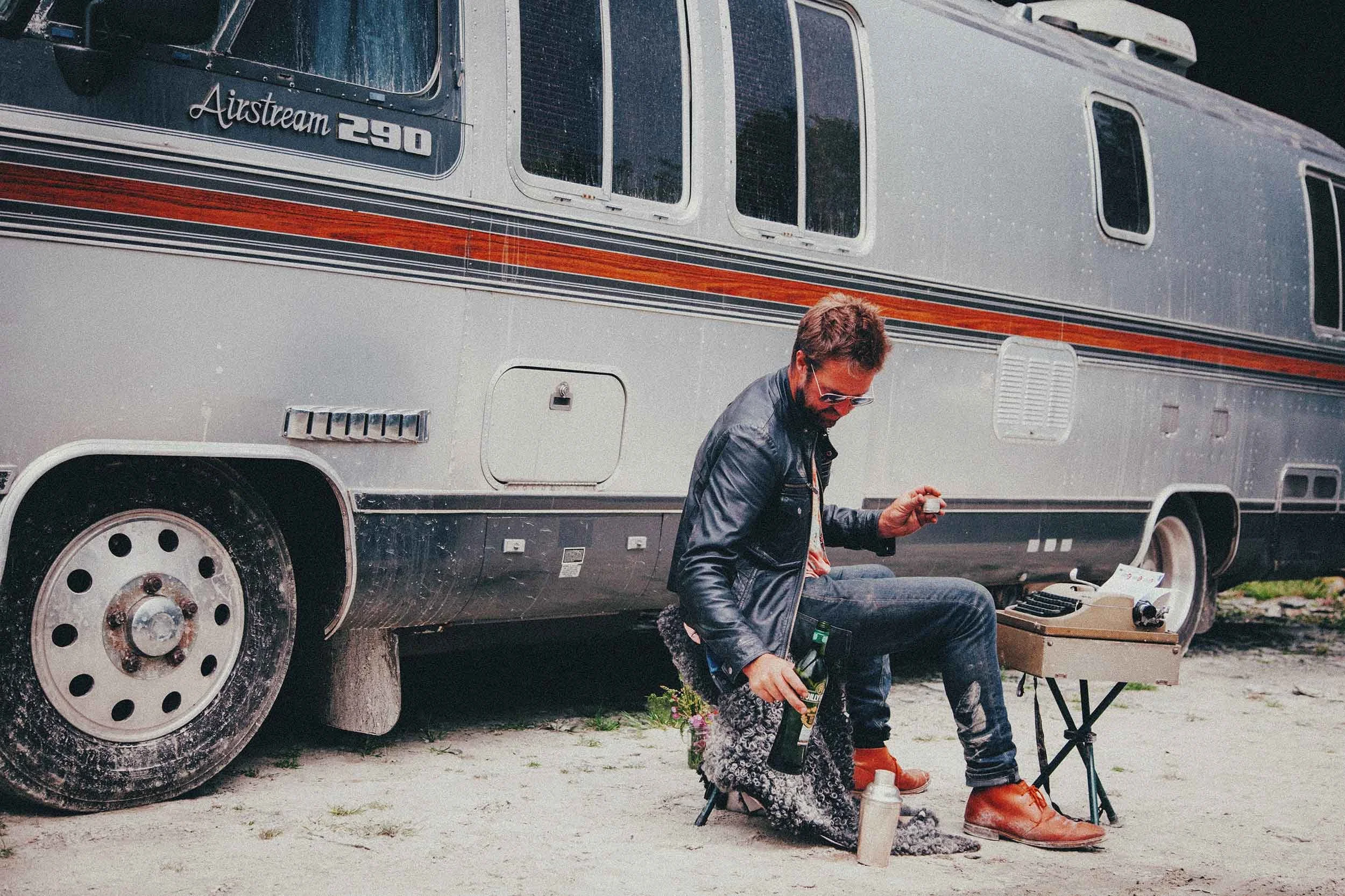 Editorial lifestyle photograph of man beside vintage Airstream trailer, outdoor brand imagery in natural light