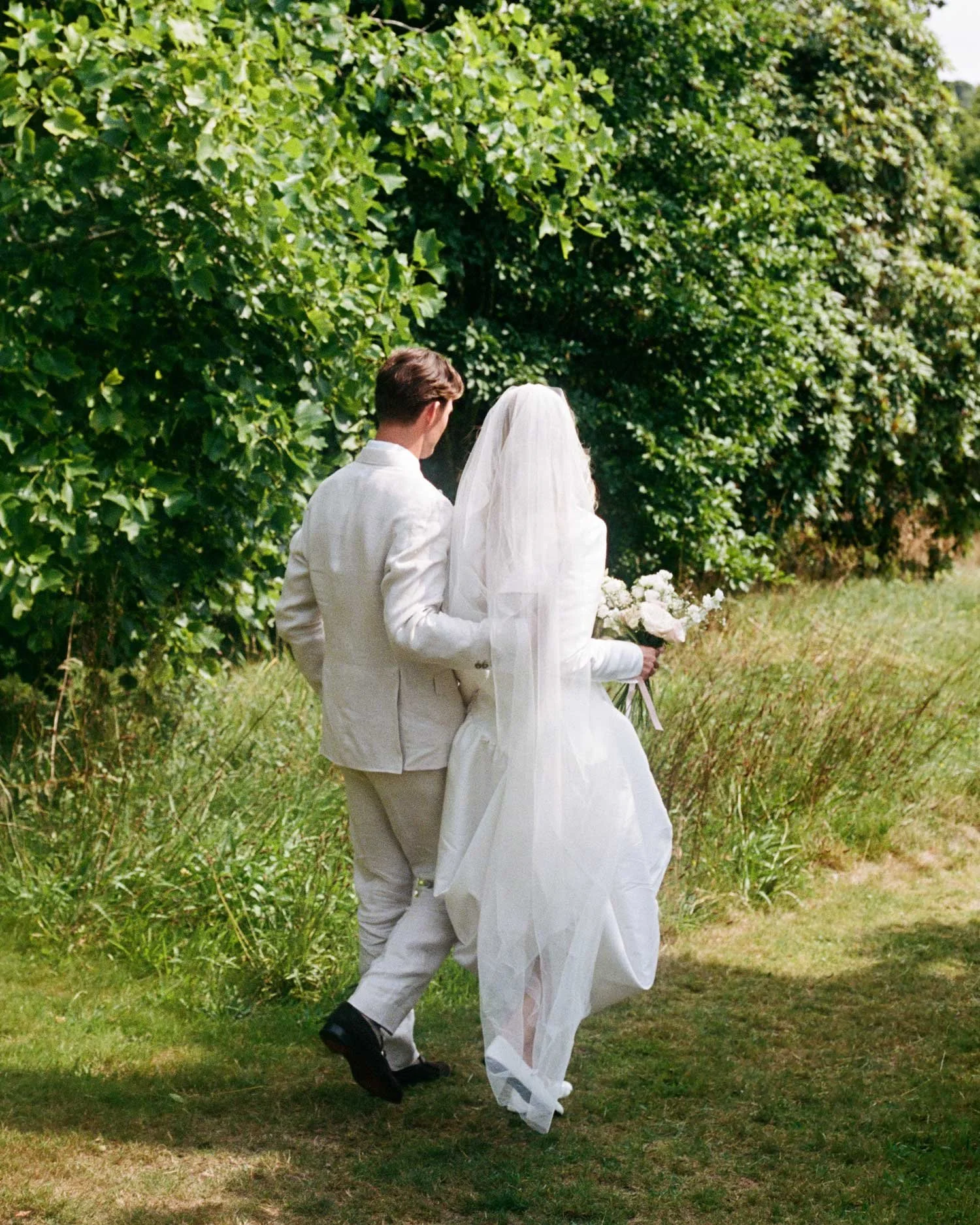 Natural light 35mm film wedding photography of couple walking through garden, relaxed documentary approach