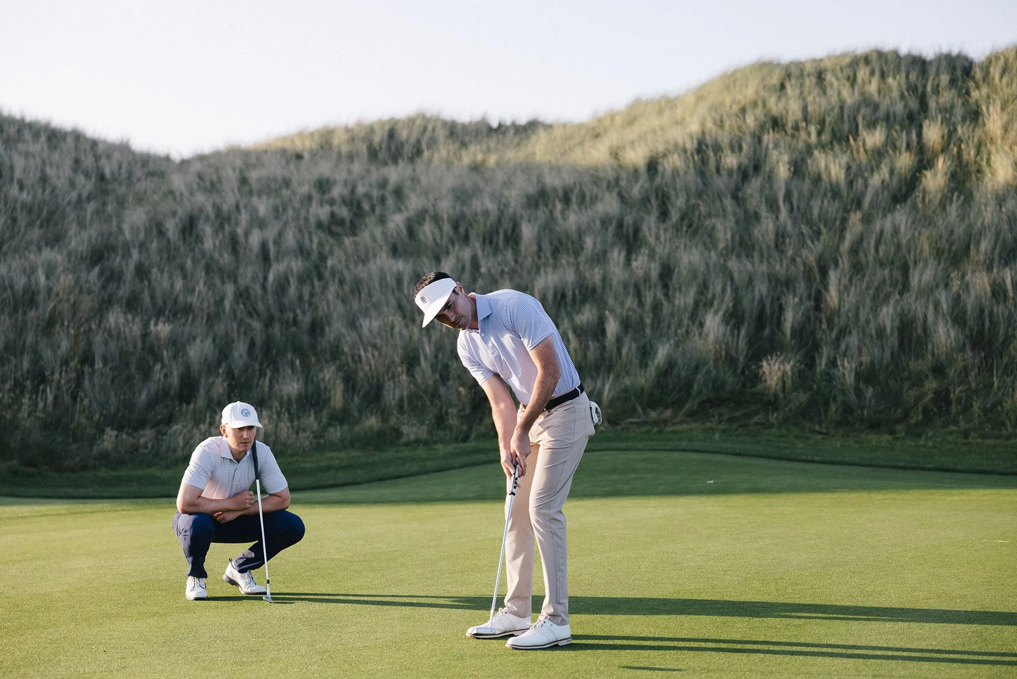 Two golfers reading a putt together on a links green