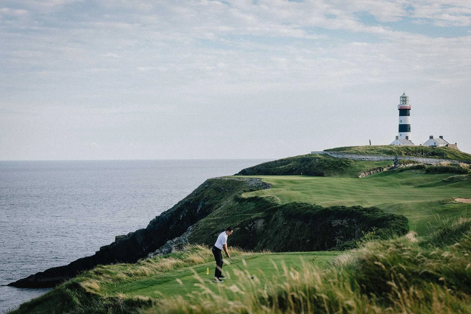 Golfer beneath the lighthouse on the cliffs at Old Head Golf Links