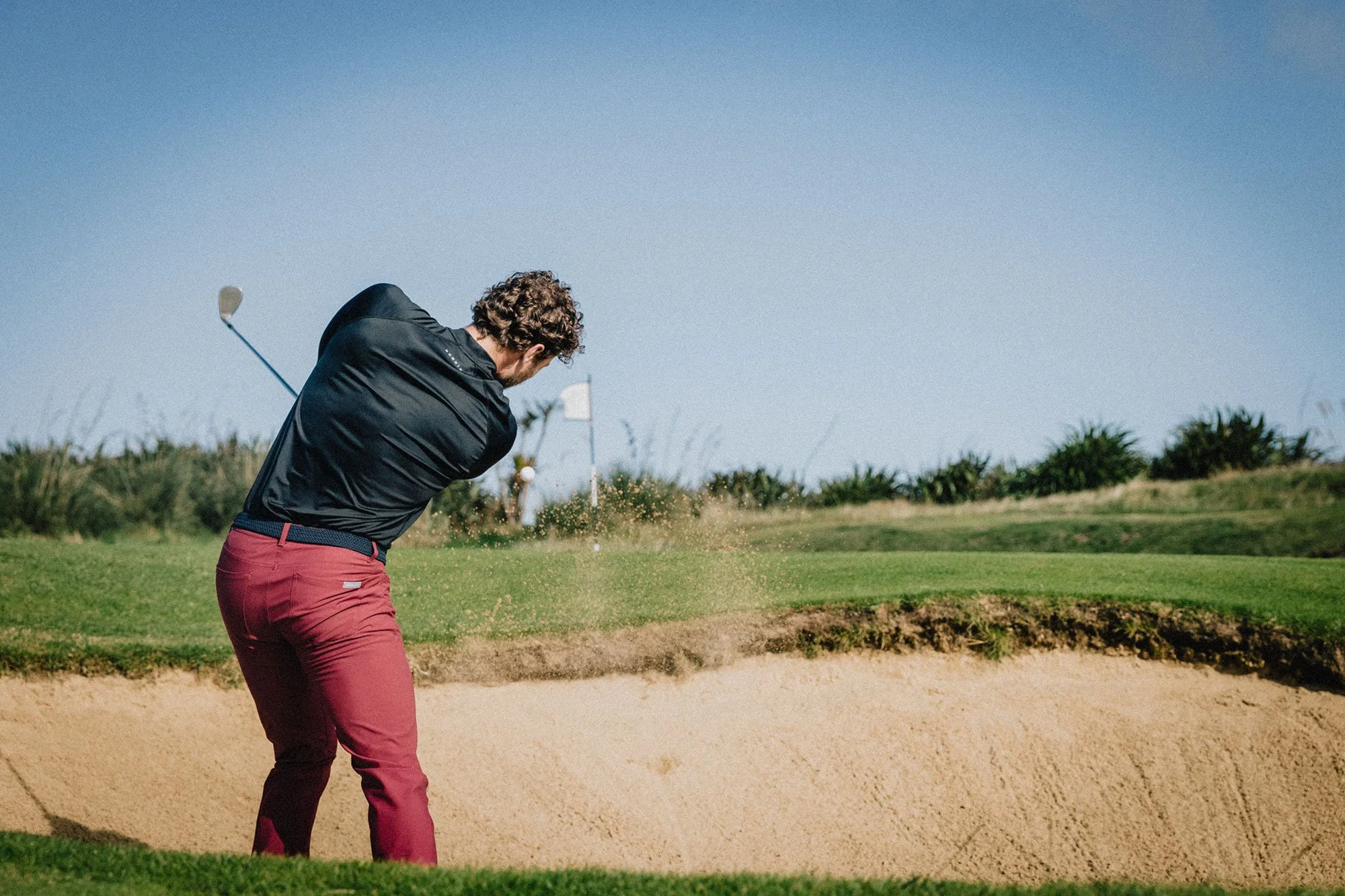 Golfer playing a bunker shot at Old Head Golf Links on the coast of Ireland