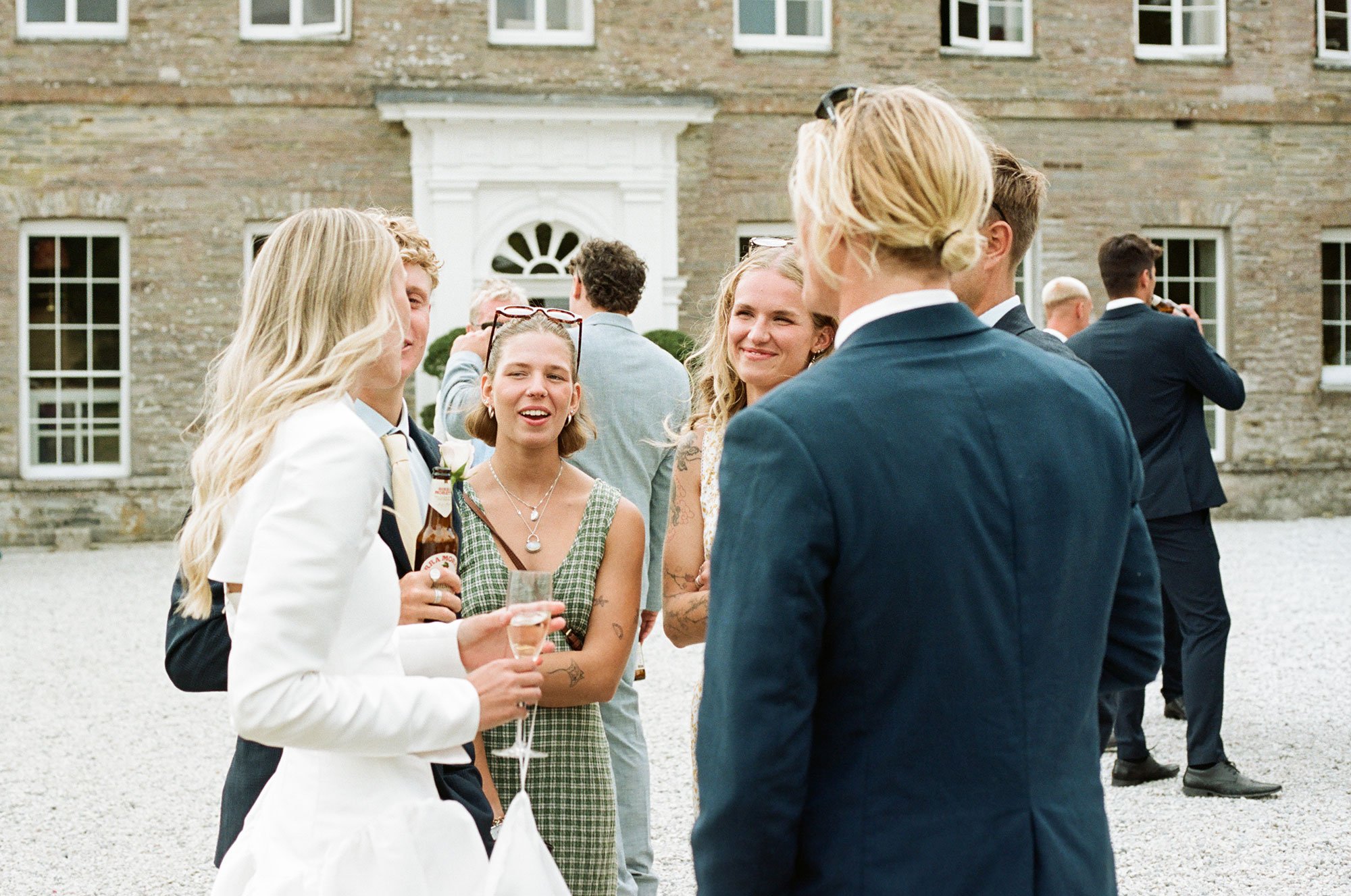 Wedding guests talking outside Boconnoc House photographed in a documentary style