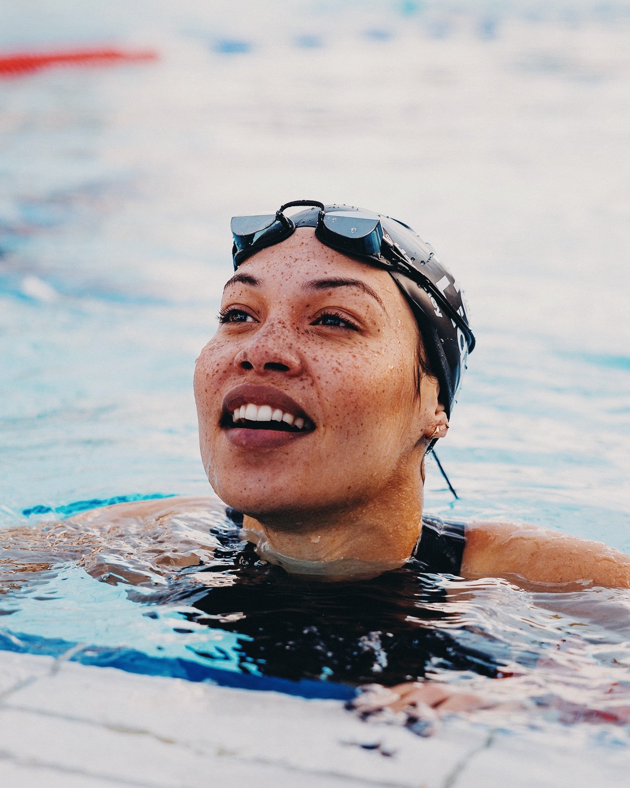 Lifestyle sports portrait of female swimmer in outdoor pool, natural light brand photography