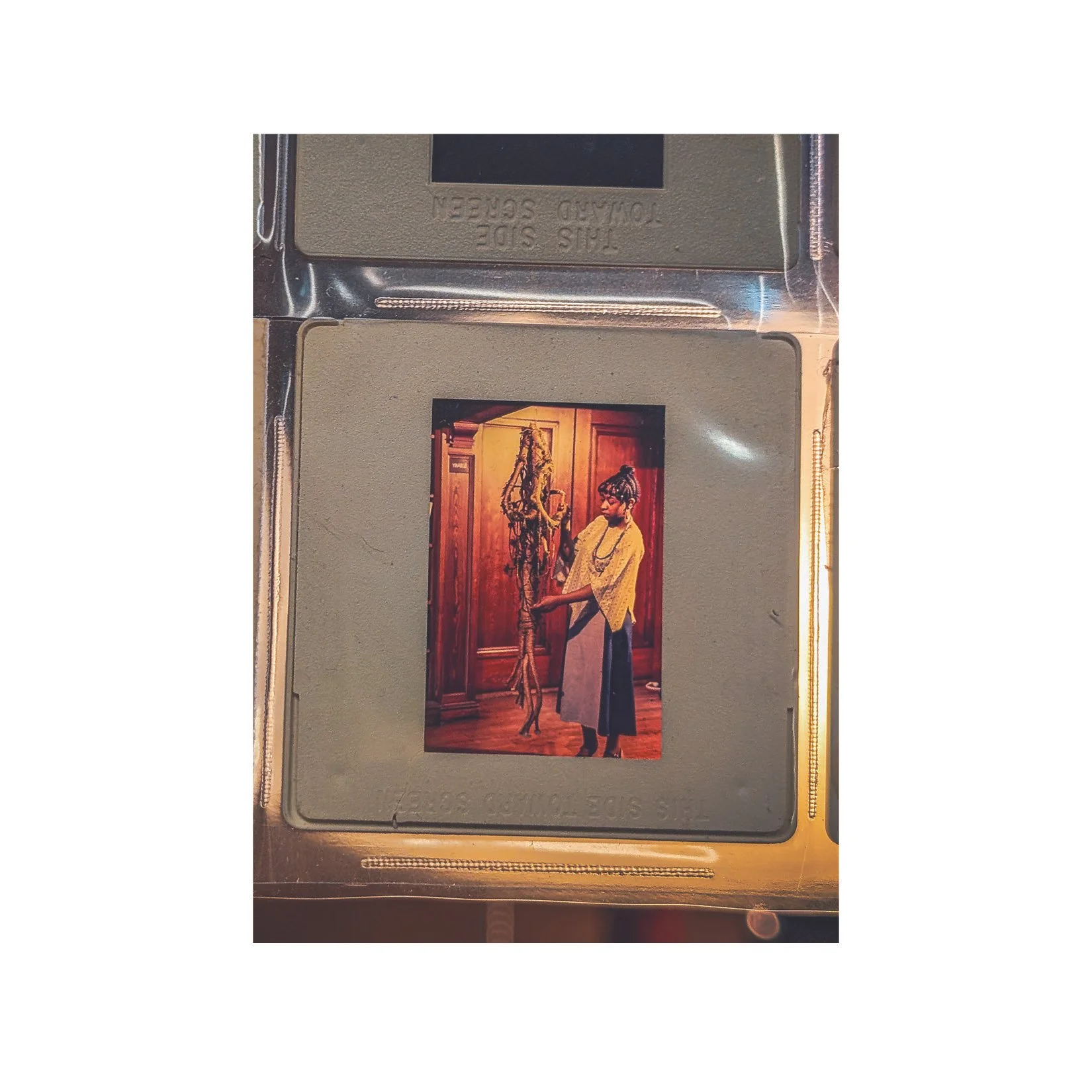 In this slide, Theresa stands beside here fiber art structure entitled "Tree." (UMass Boston Archive)