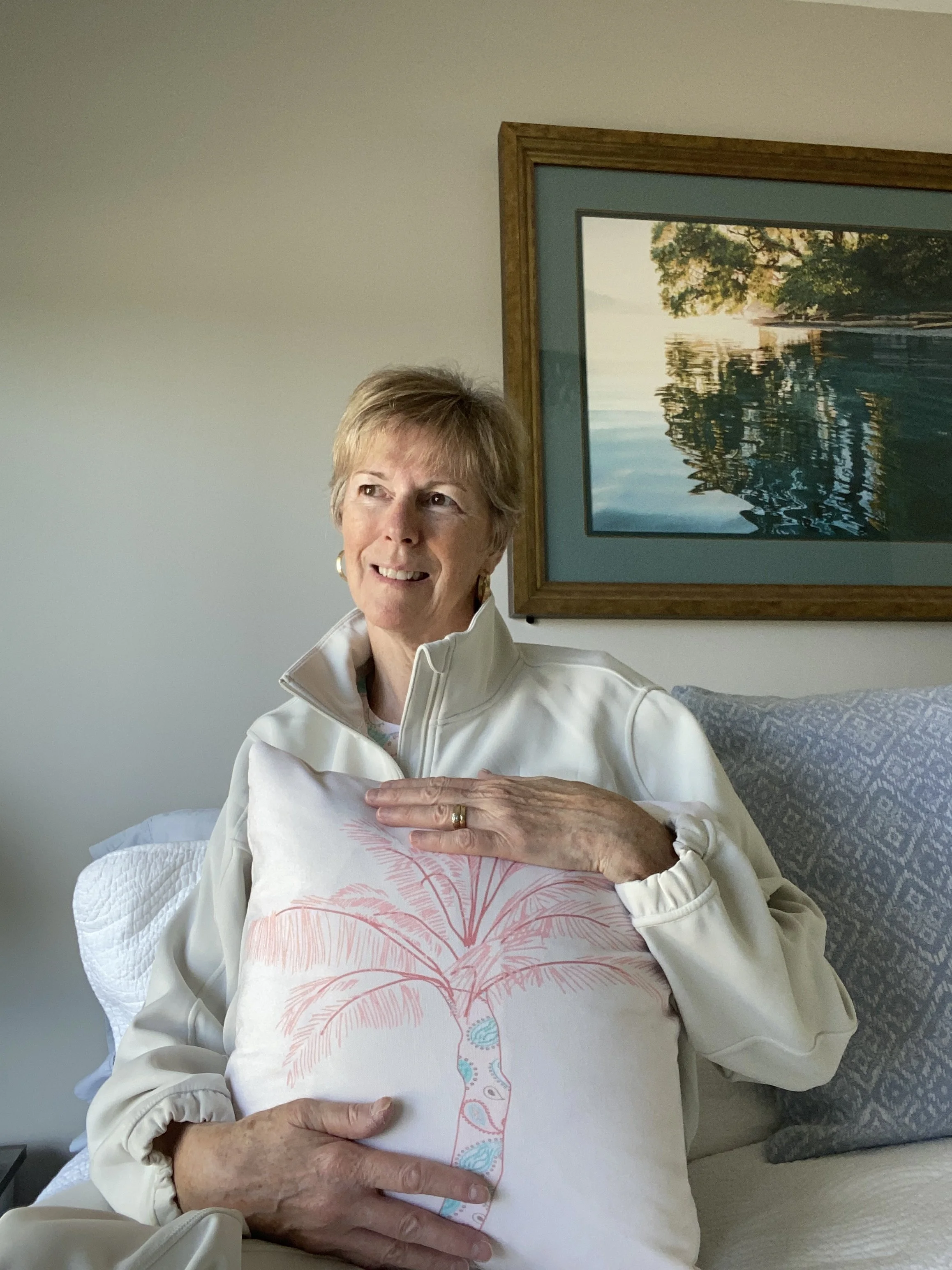 Artist Kelly Edmonds holding a pillow featuring her hand-drawn palm illustration, representing her transition to Curious Shapes Studio and a new chapter in art and design.