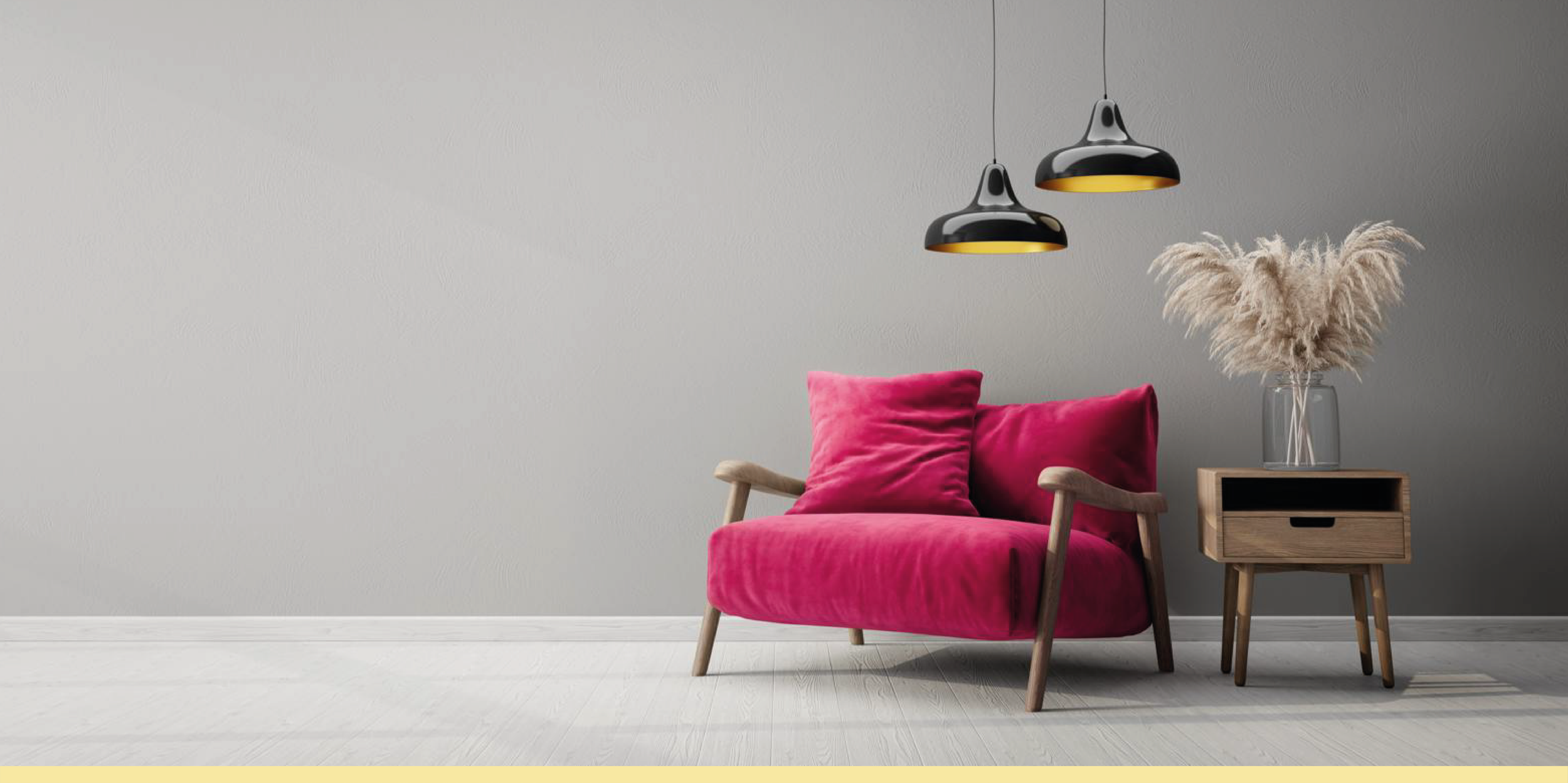 Un fauteuil rose en velours avec un coussin rose, à côté d'une petite table en bois avec une vase contenant des pampas.