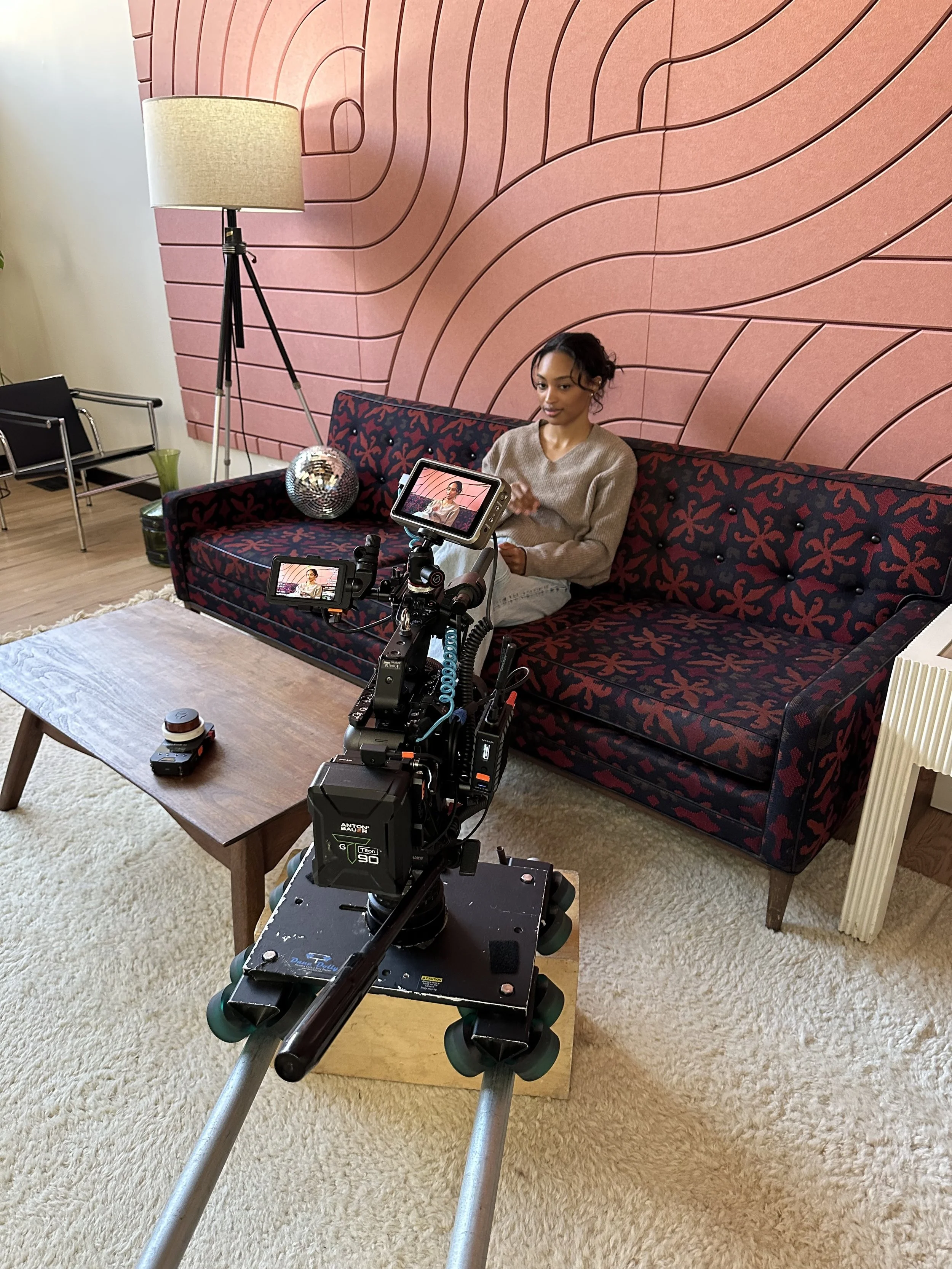 Camera on dolly tracks filming a woman on a couch for the Udio brand film