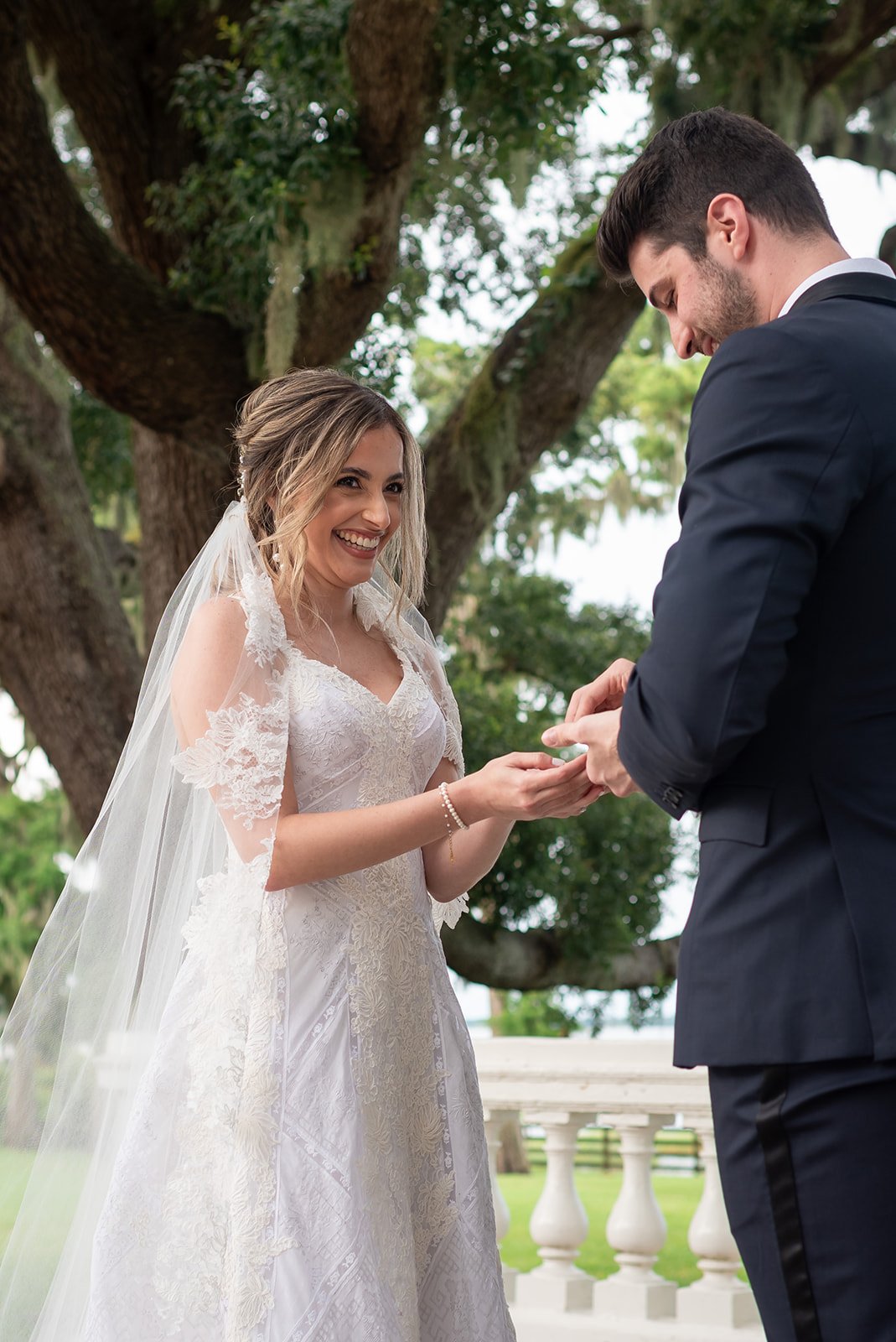 Bride and groom exchanging rings outdoors during a wedding ceremony.