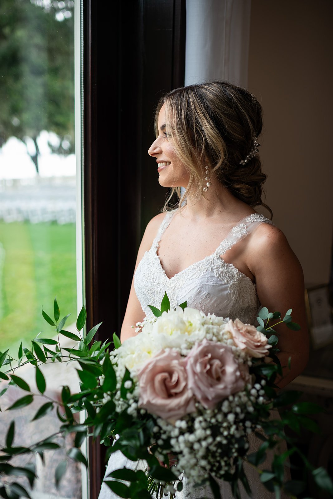 Bride holding a bouquet, looking out a window