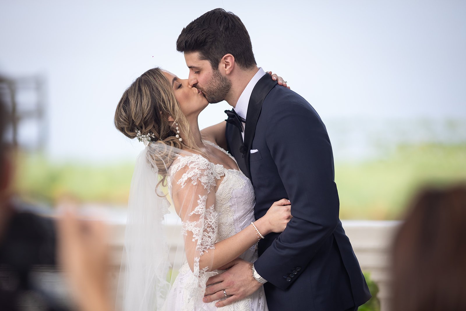 Bride and groom kissing at a wedding ceremony outdoors.