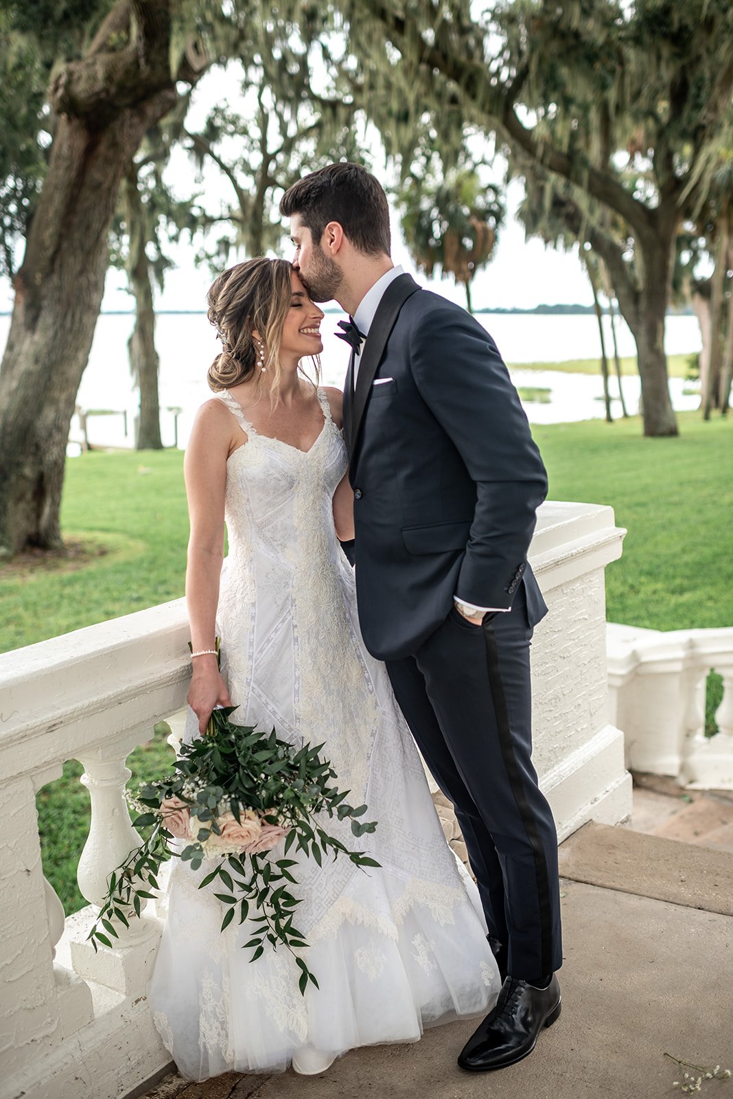 Bride and groom embracing outdoors, bride holding bouquet.