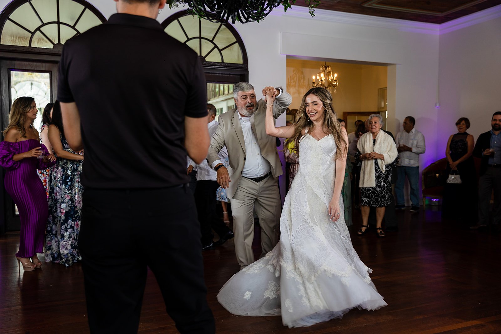 A bride dancing with an older man at a wedding reception, as guests watch and enjoy the event.