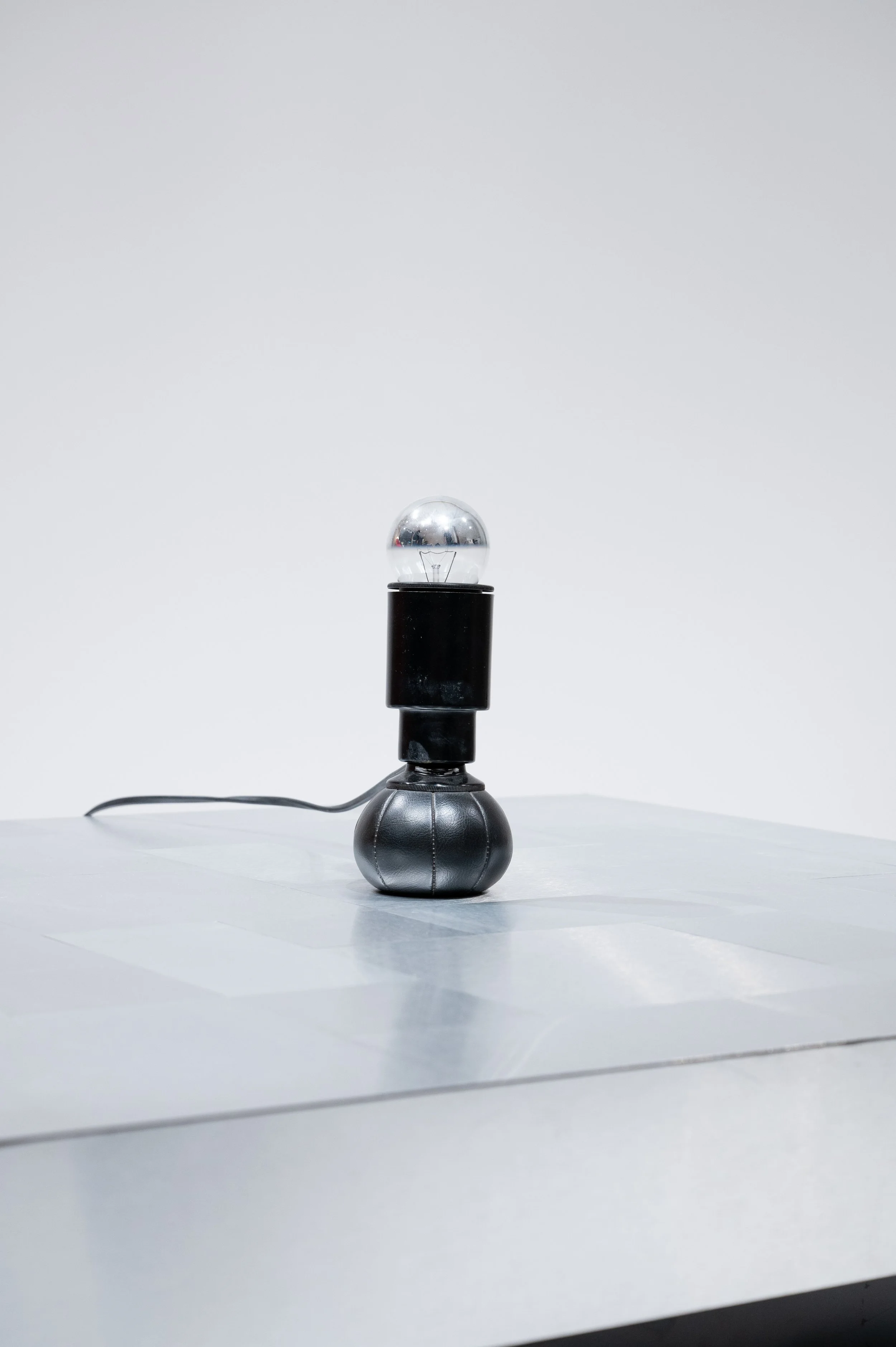 Lampe design avec un interrupteur et une base sphérique noire sur une table grise.