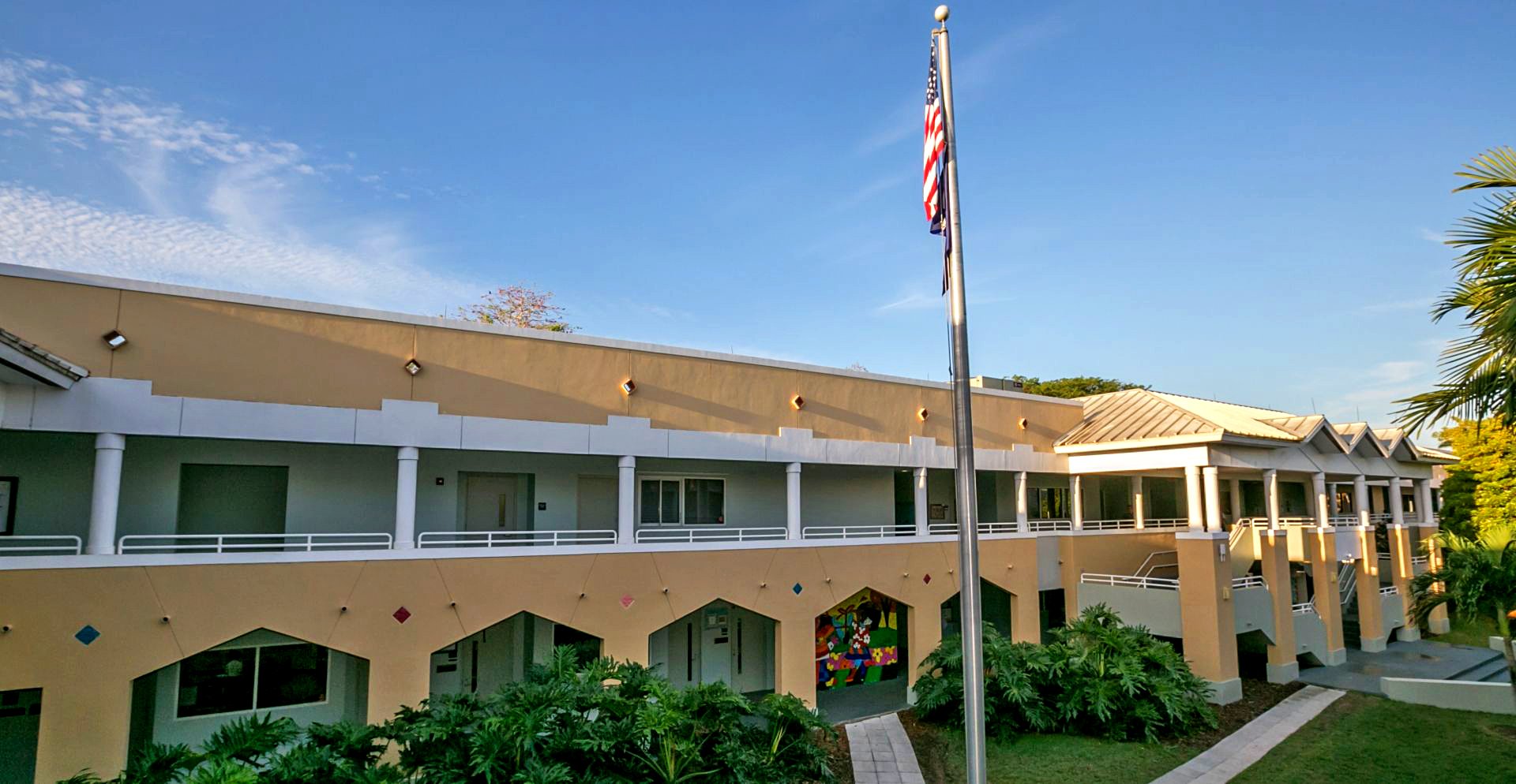 Modern school building with columns, American flag, and landscaped greenery.