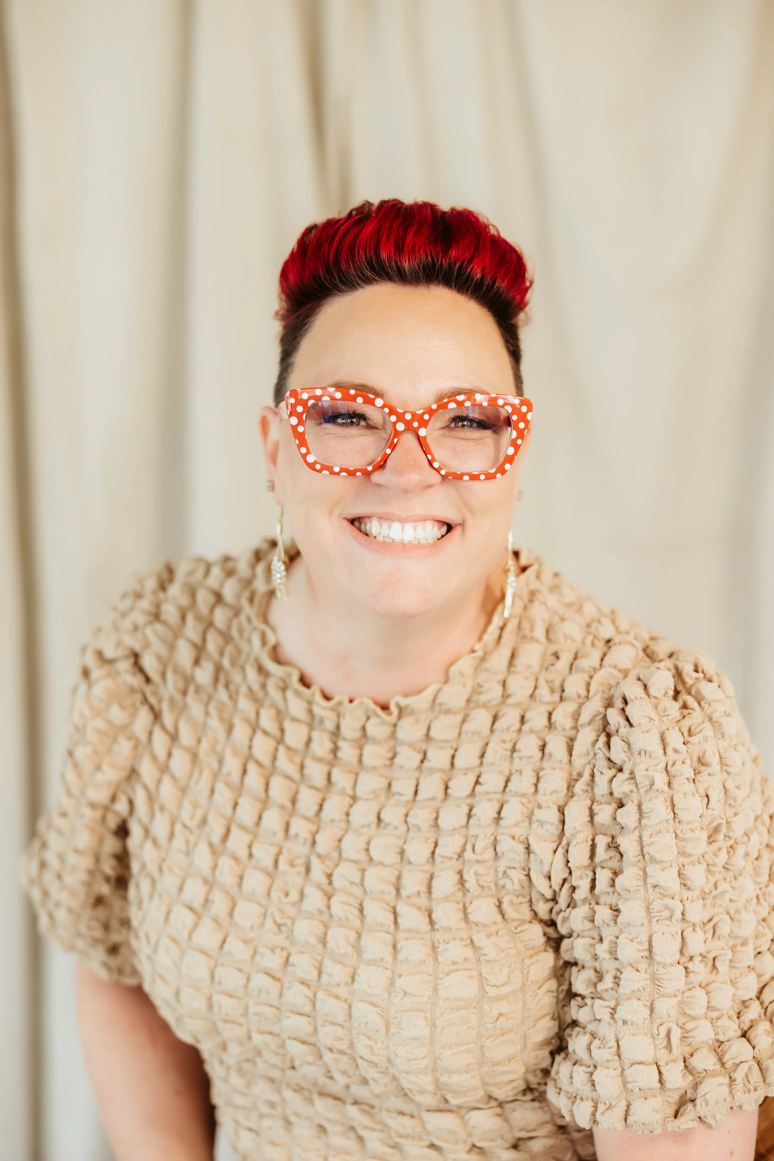 A woman smiling from ear to ear sitting on a stool