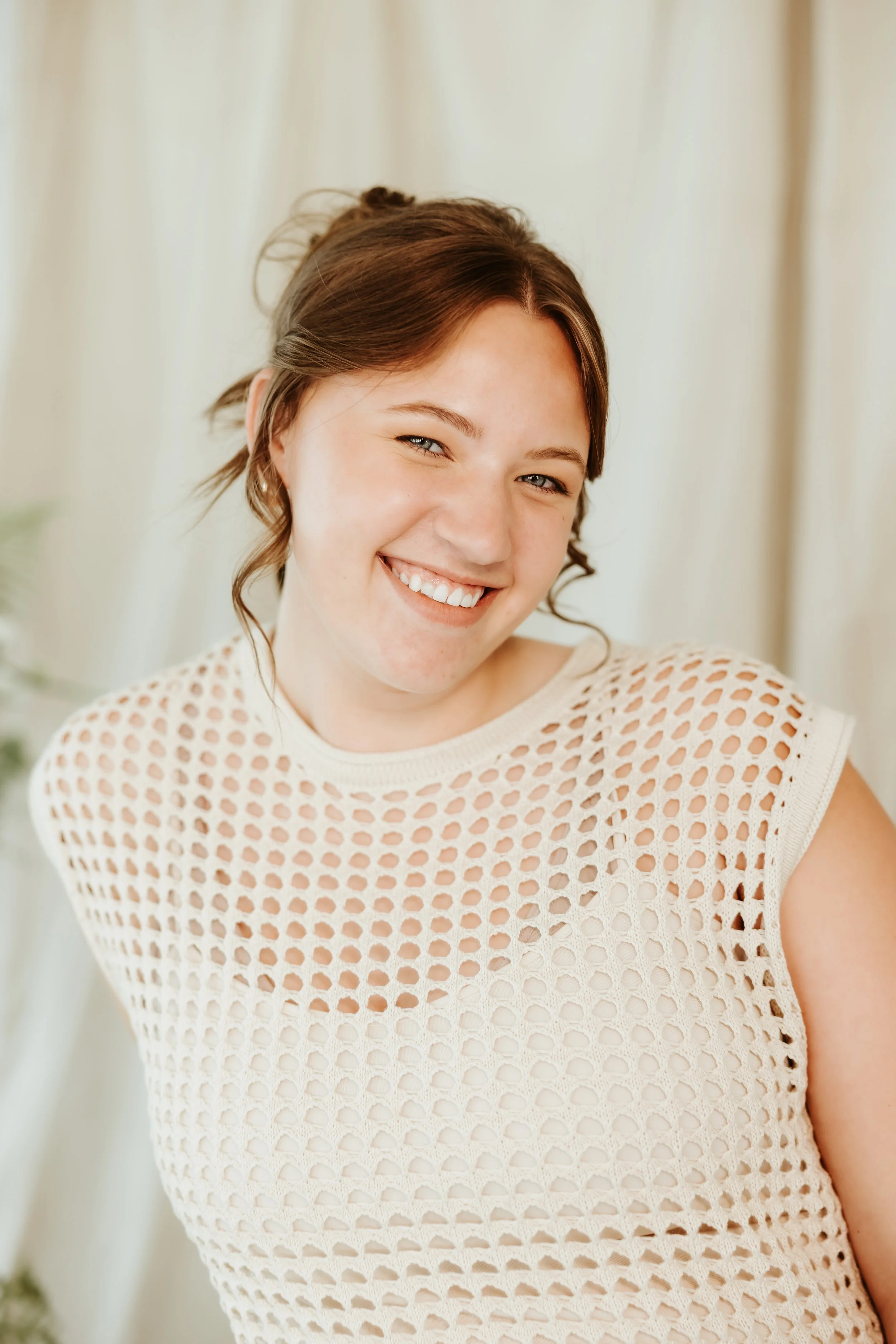 A woman sitting on a stool smiling at the camera
