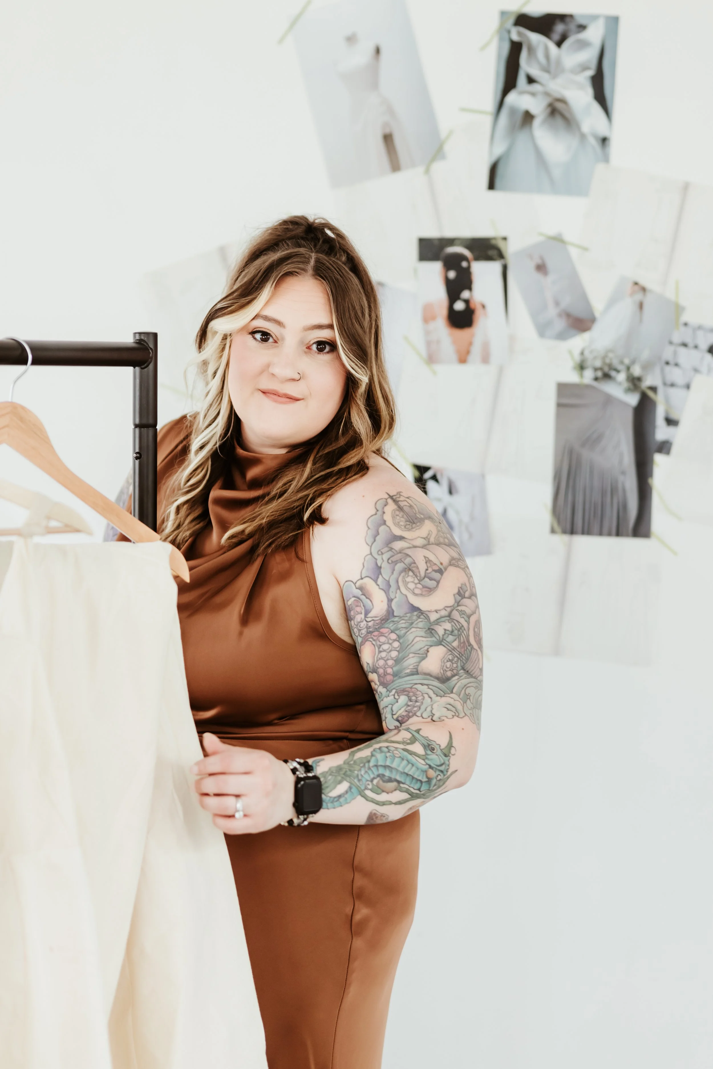 A woman standing in front of a wall holding on to a Z-rack full of dress mock-ups