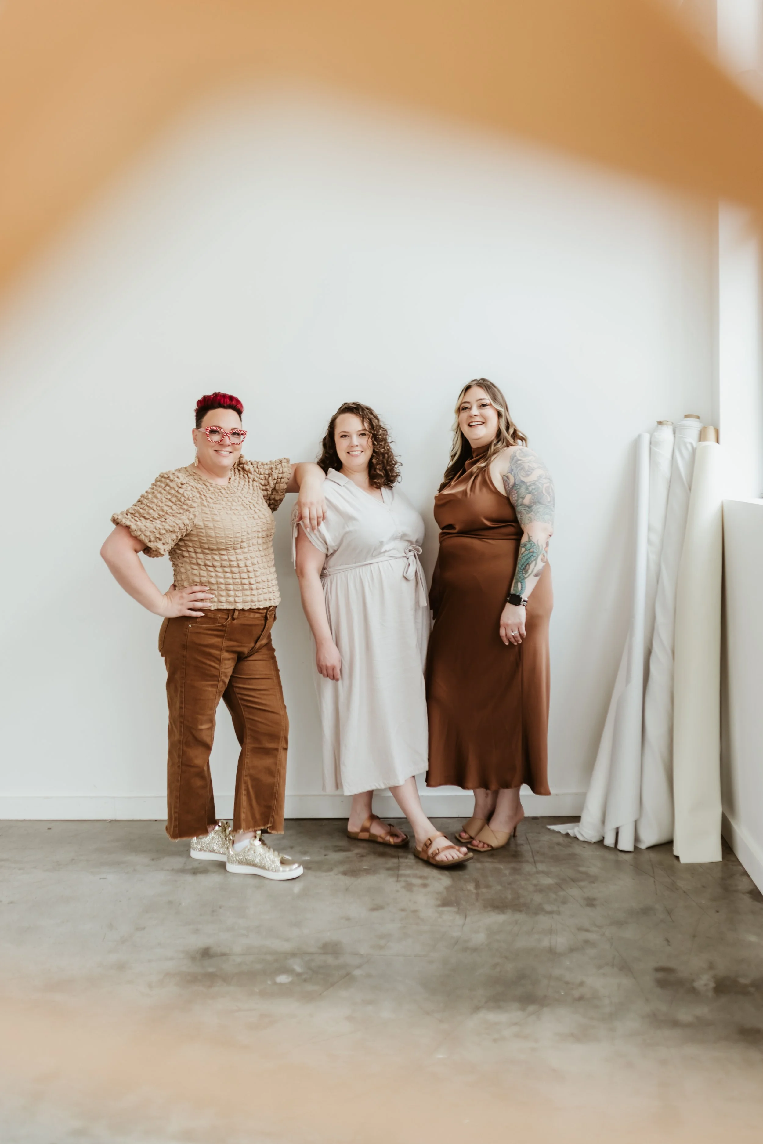 Three seamstresses standing against a wall smiling