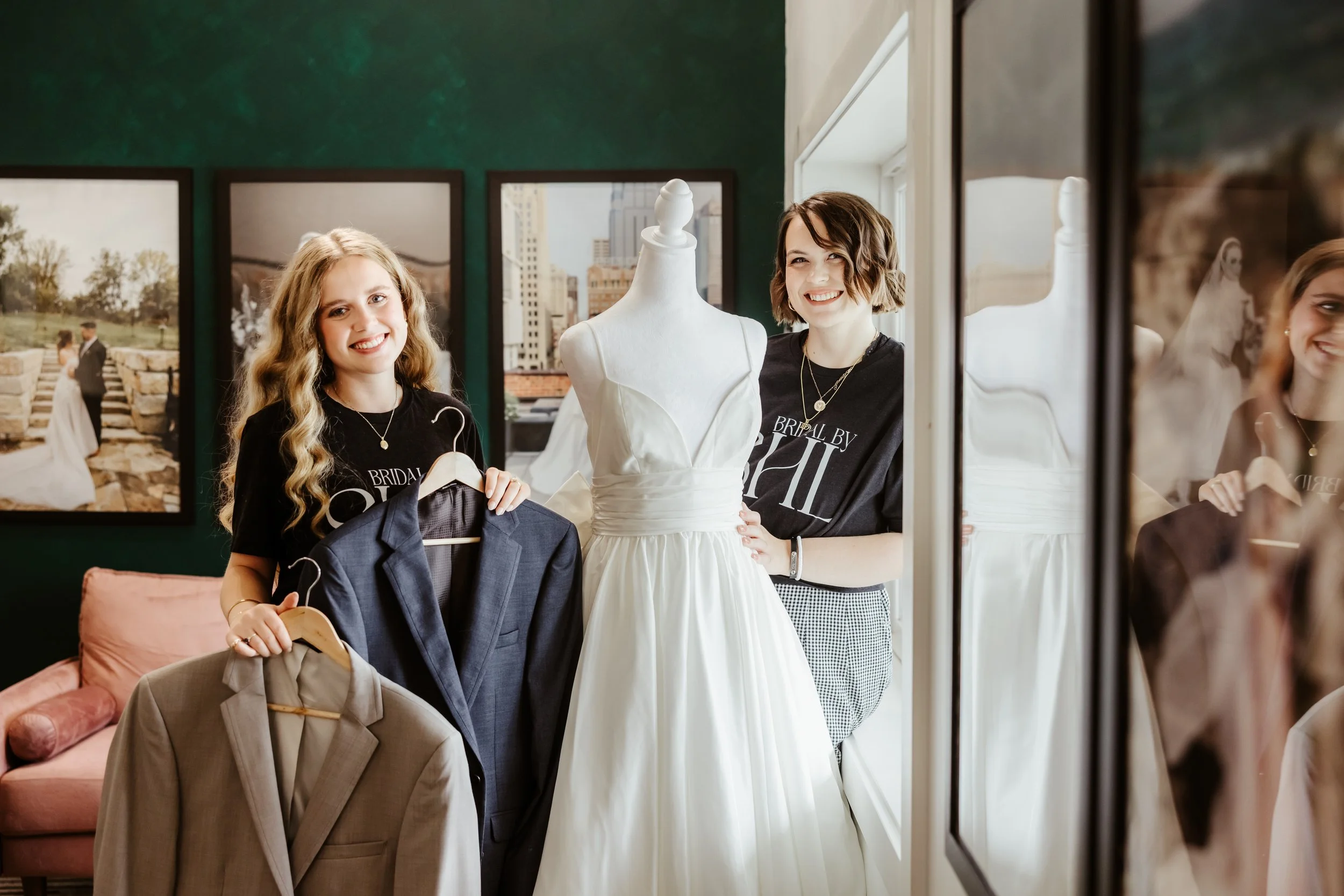 Two bridal stylists standing near a mannequin showing off a dress and suit