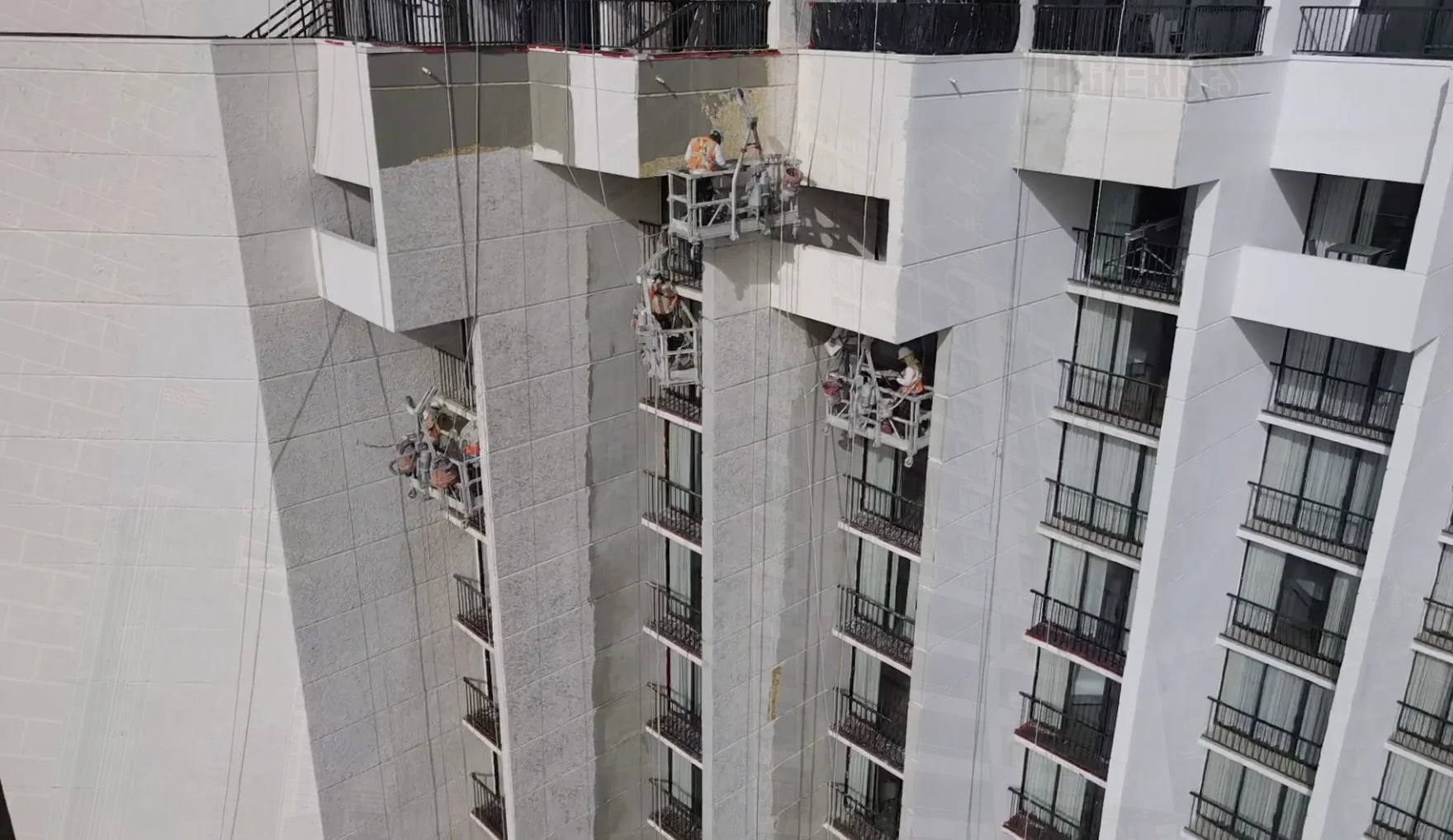 Pilot crews resurfacing and smoothing aged stucco on a high-rise hotel