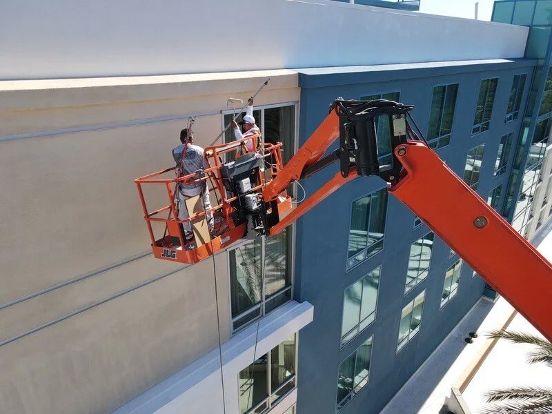 Pilot Painting crews using a boom lift to paint a multi-story commercial buidling