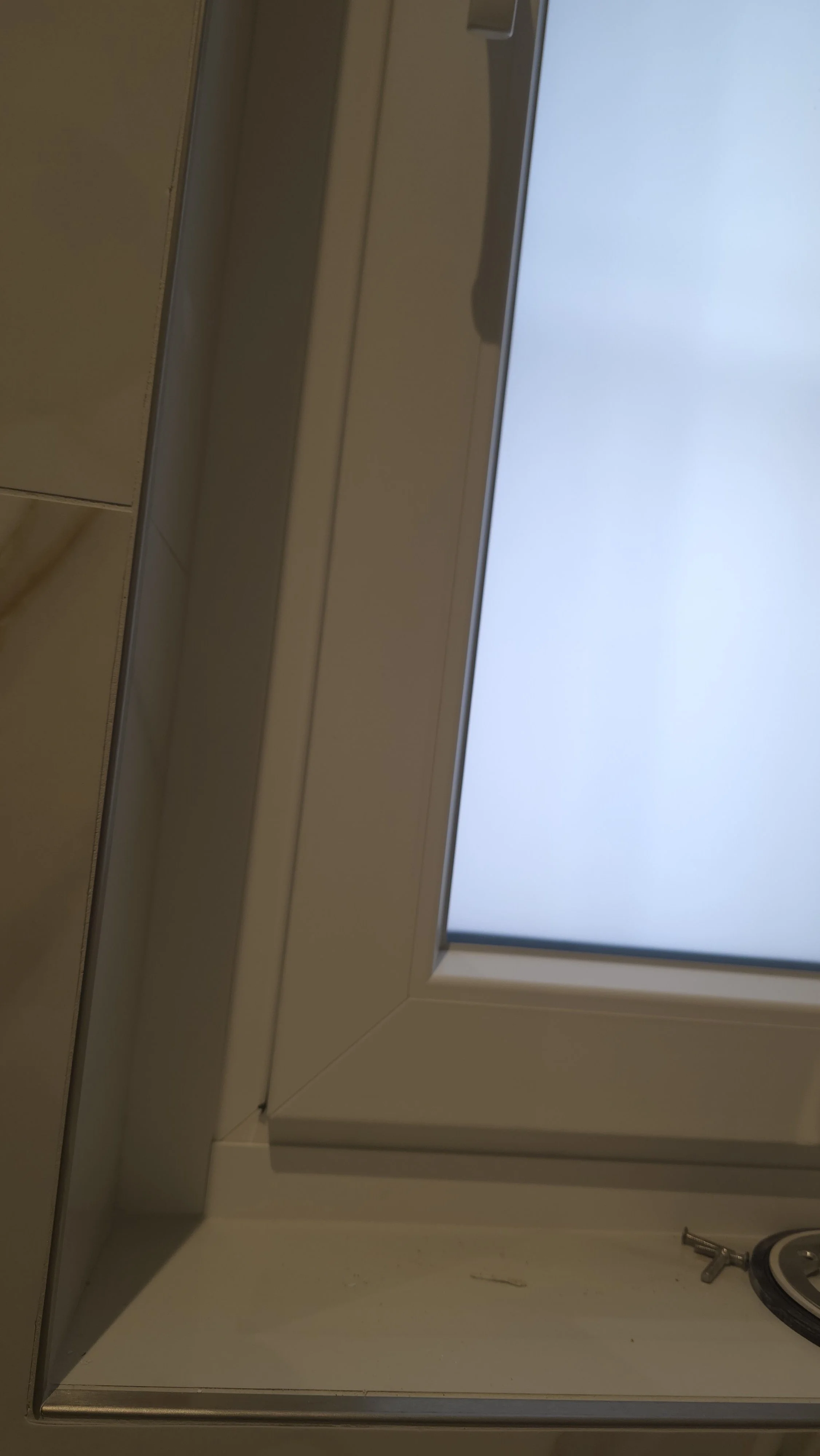 Finestra con telaio bianco e vetri chiusi, vista verso il cielo grigio.