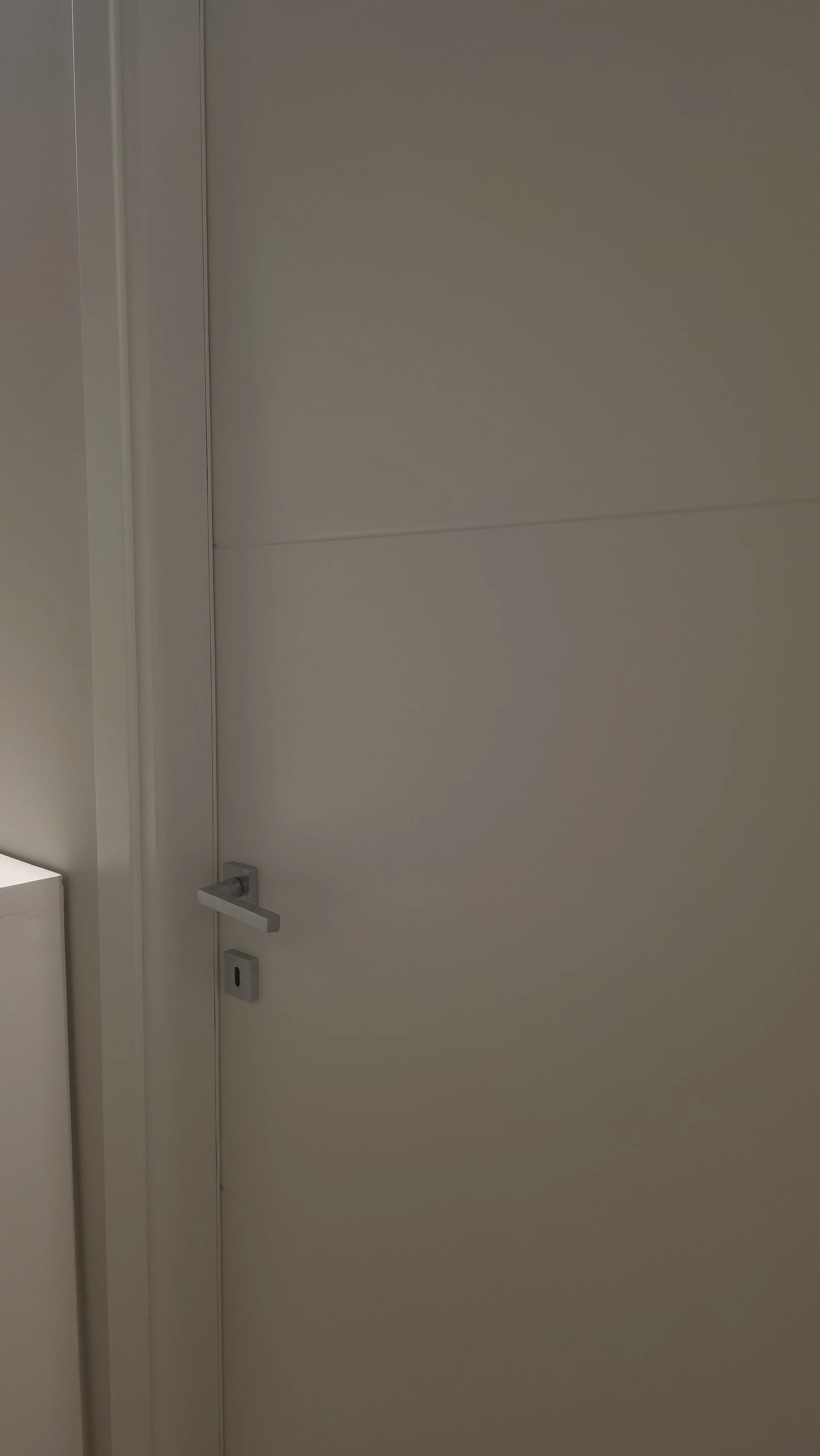 Porta bianca in una stanza con maniglia e tastiera di sicurezza