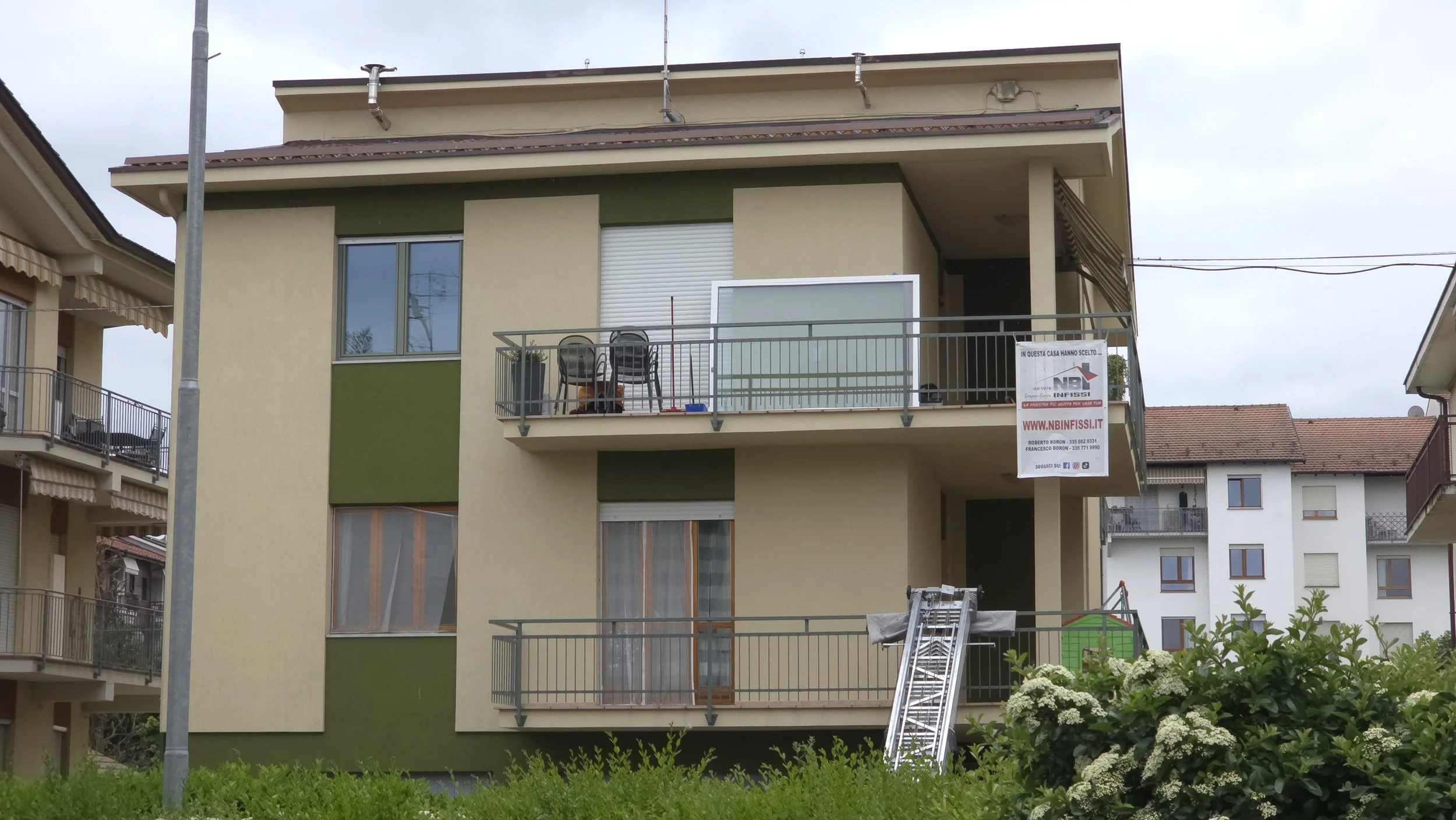 Facciata di un edificio residenziale con balconi e finestre, con un cartello di vendita affisso al balcone del primo piano.