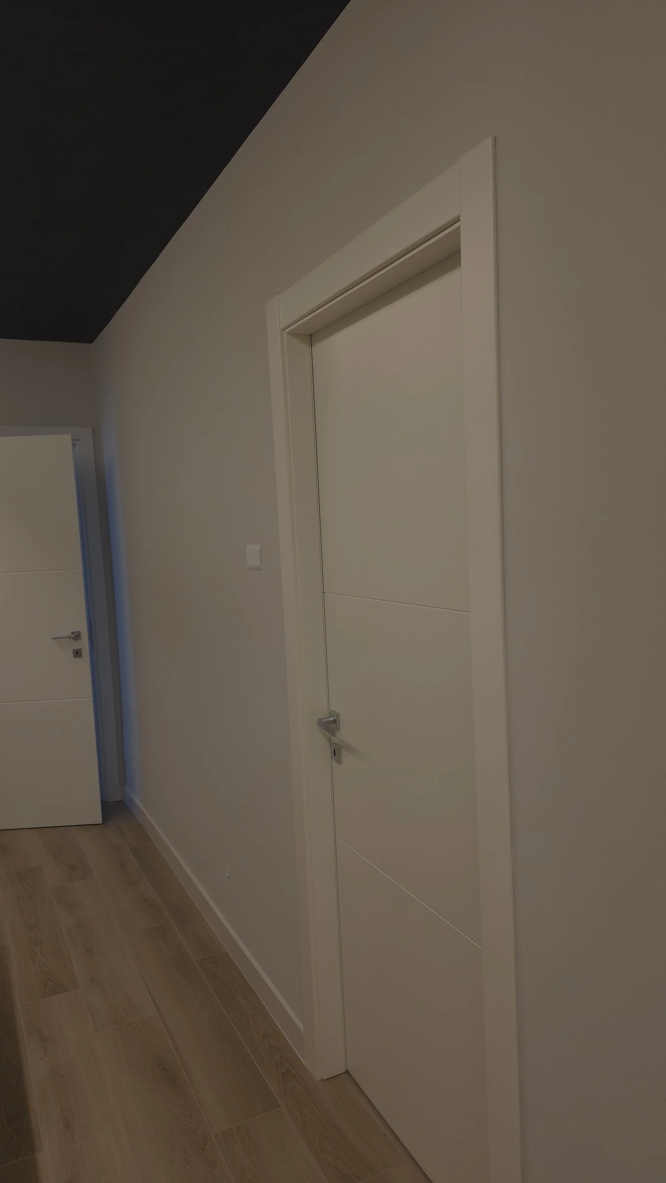 Porta bianca in una casa con pareti bianche e pavimento in legno