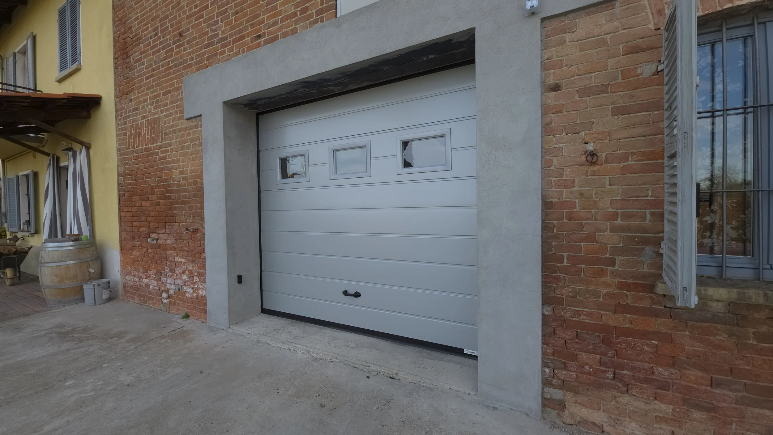 Garage con porta sezionale bianca in un edificio di mattoni rossi.