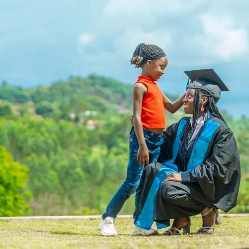 A graduating student kneels in front of a child