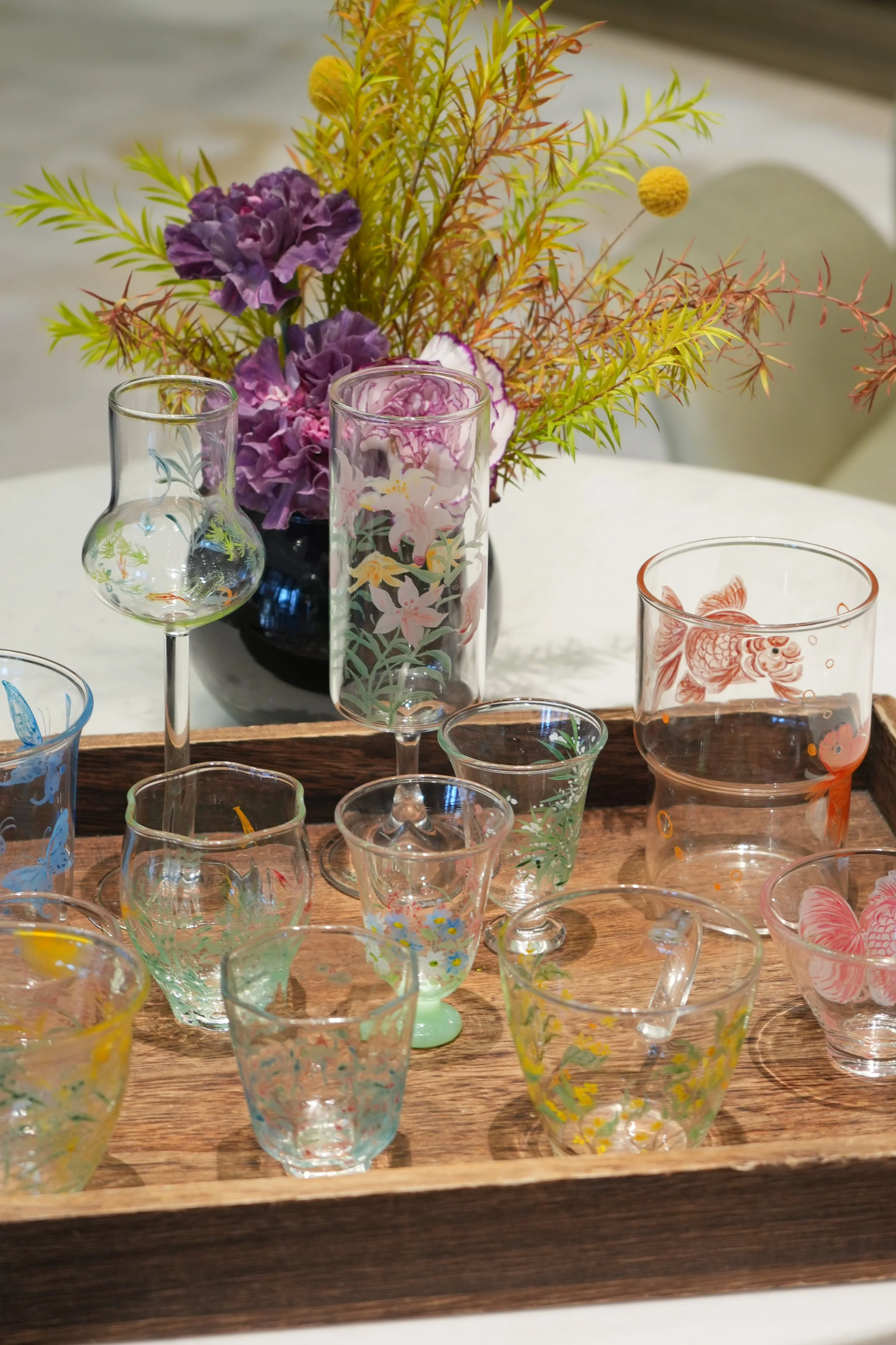 A photograph of several hand-painted glass cups, all varying in size and aesthetic.