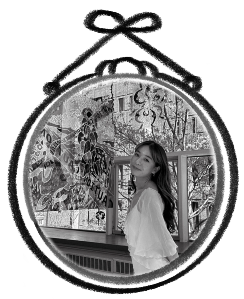 A small, circular black-and-white photograph of a young woman in a flowing white dress posing next to a hanging glass poster. A hand-drawn frame encircles the photo, making it seem like it is being hung on a wall.