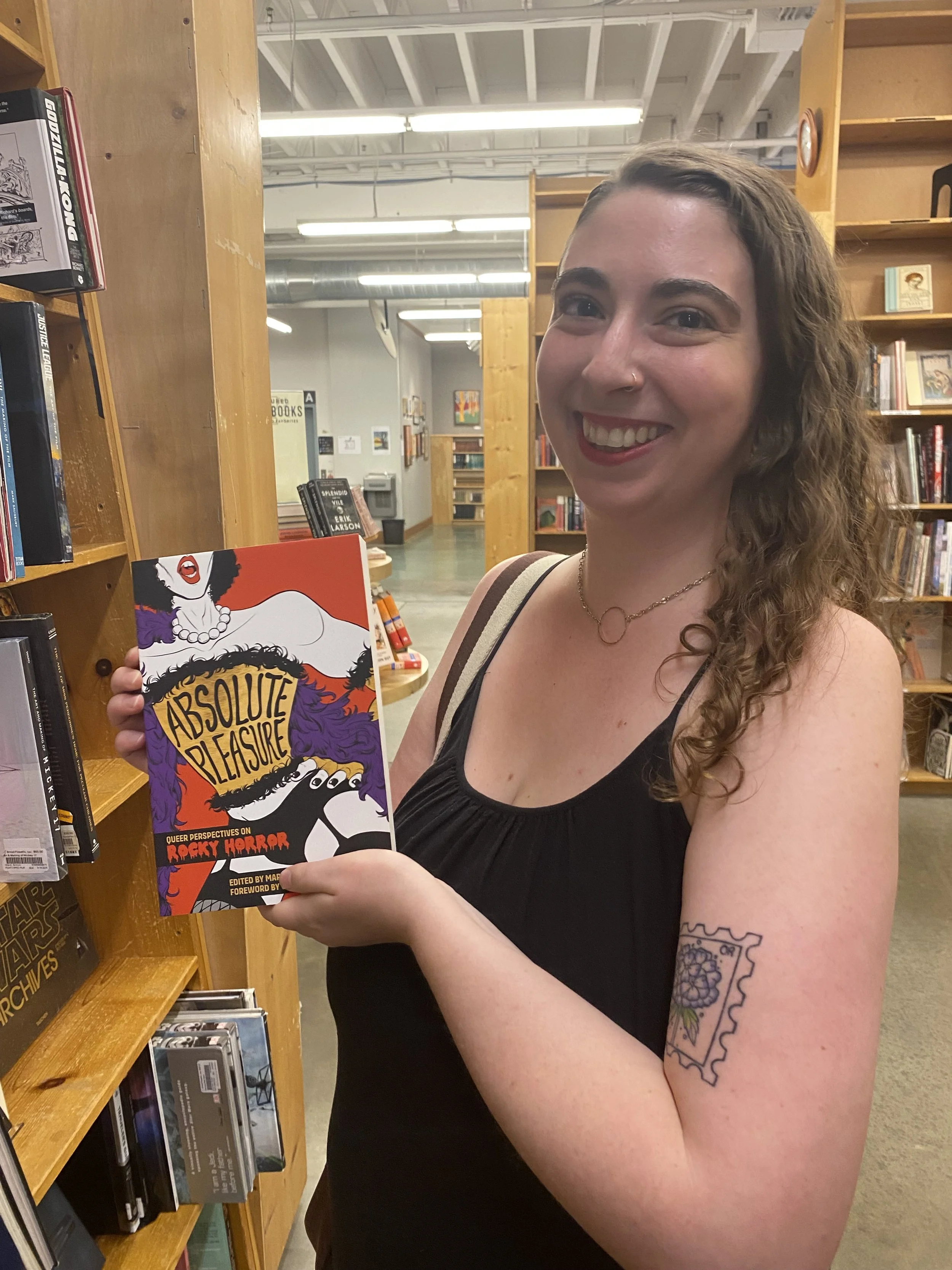 Aliya holding a copy of the Absolute Pleasure anthology in Powells.