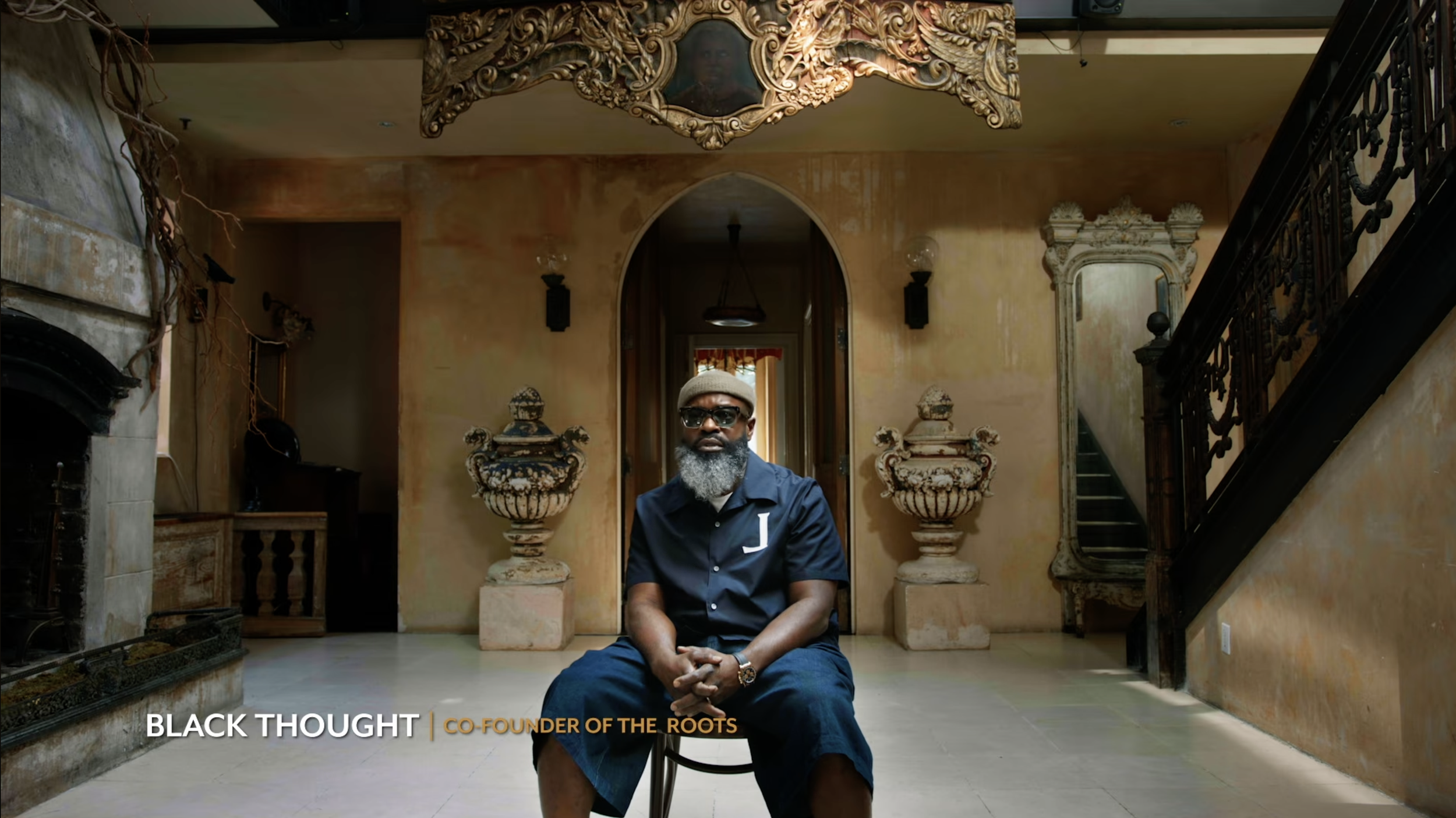 Blackthought from The Roots sitting in a decorated room for an interview.
