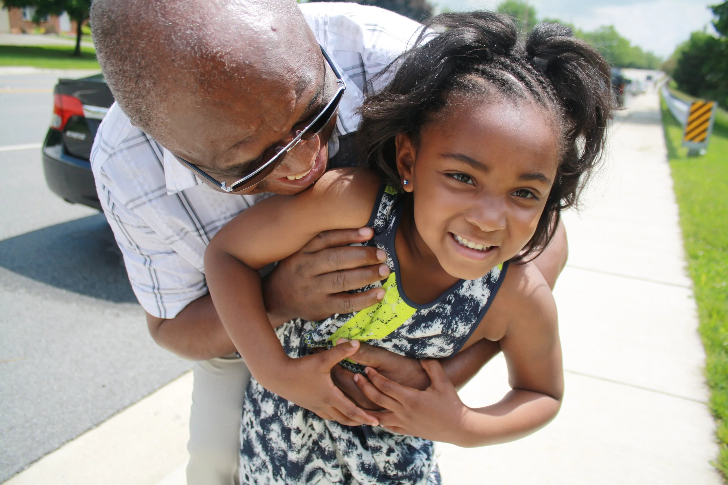 Daisy photographs her father embracing his granddaughter outside of her pre-K graduation ceremony (Baltimore, 2010s)