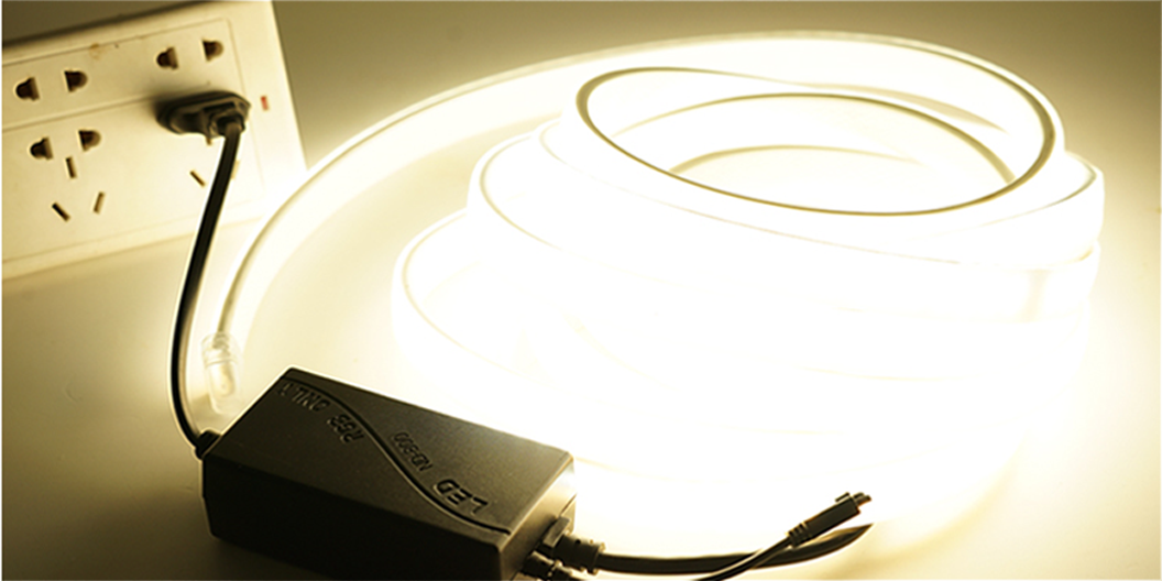 A coiled LED light strip plugged into an electrical outlet.