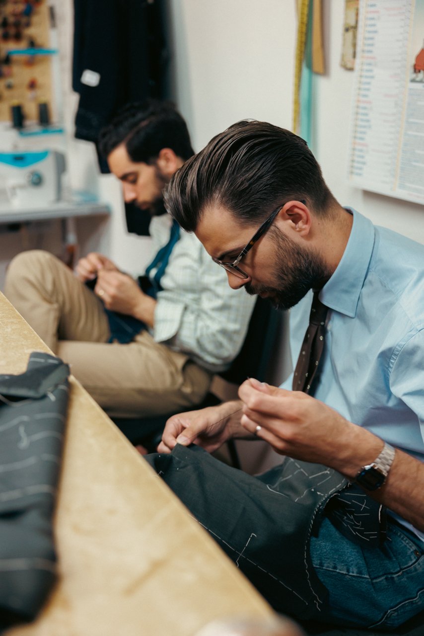 Close-up of two Liverano tailors diligently hand-stitching suit components.