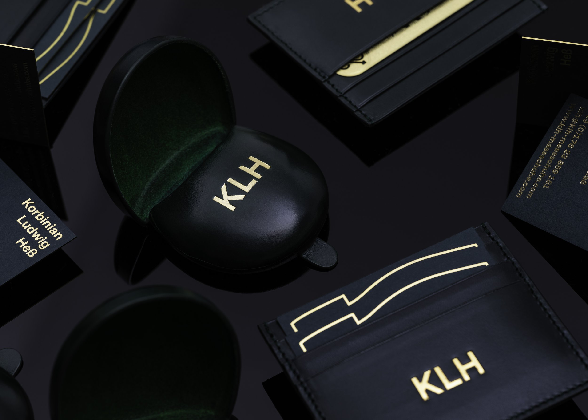 KLH monogrammed luxury leather goods including cardholder and case on black background.
