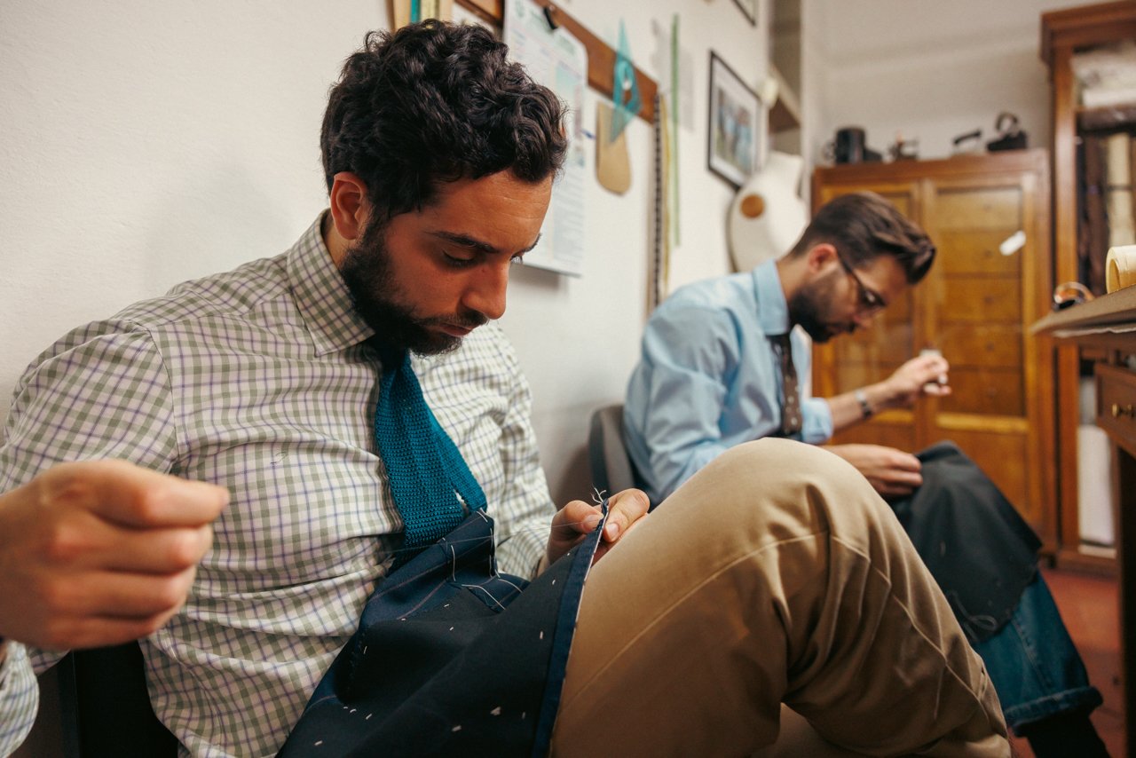 Liverano tailors sitting together, focused on hand-sewing bespoke garments.